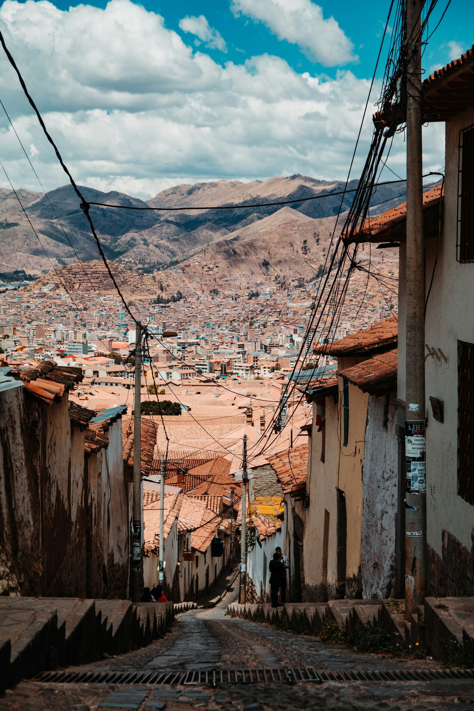 A narrow street leading to Cusco, Peru with mountains in the background.