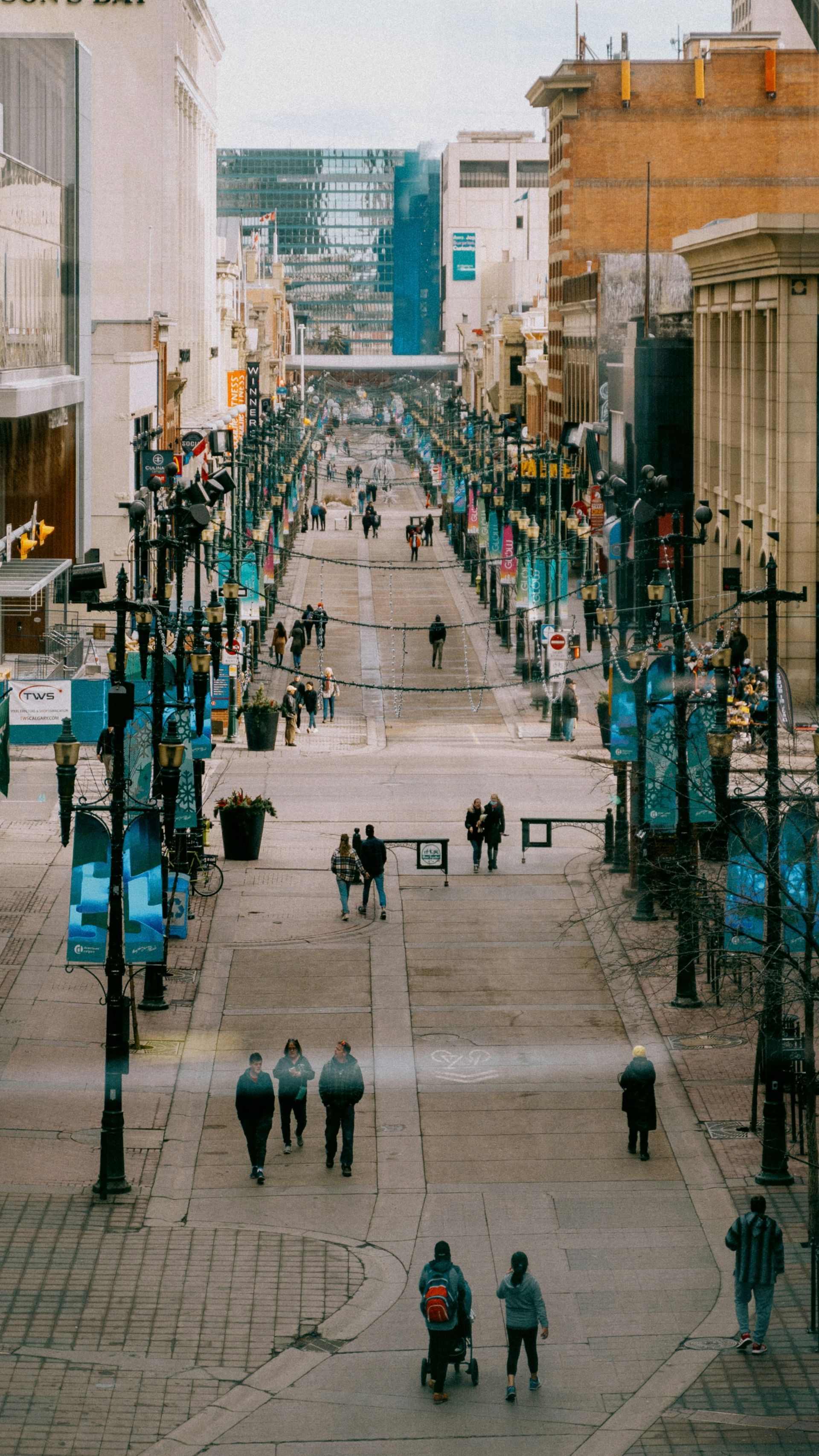 A long pedestrian street lined with shops and buildings, with people walking in the distance.