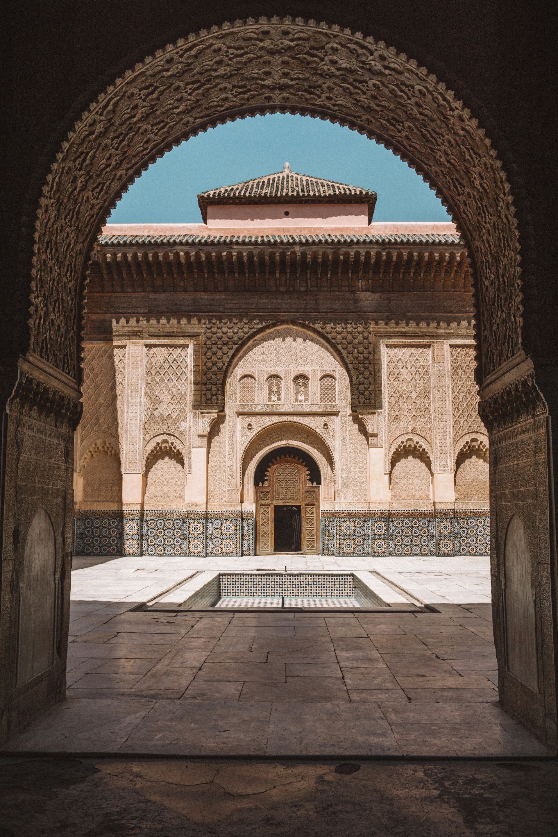 A view of a building through an archway with a fountain in front of it in Marrakesh, Morocco.