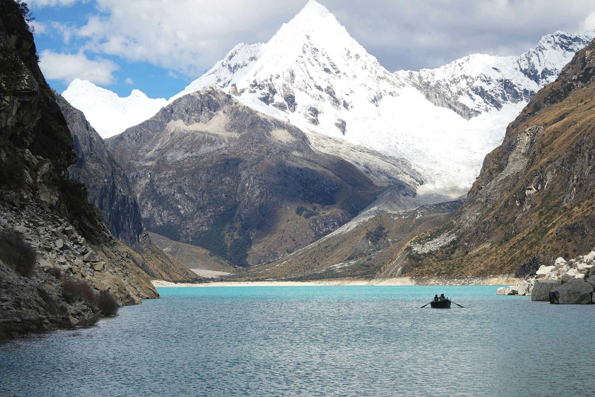 Two people in a boat on Lake Paron with mountains in the background in Huascarán, Peru.