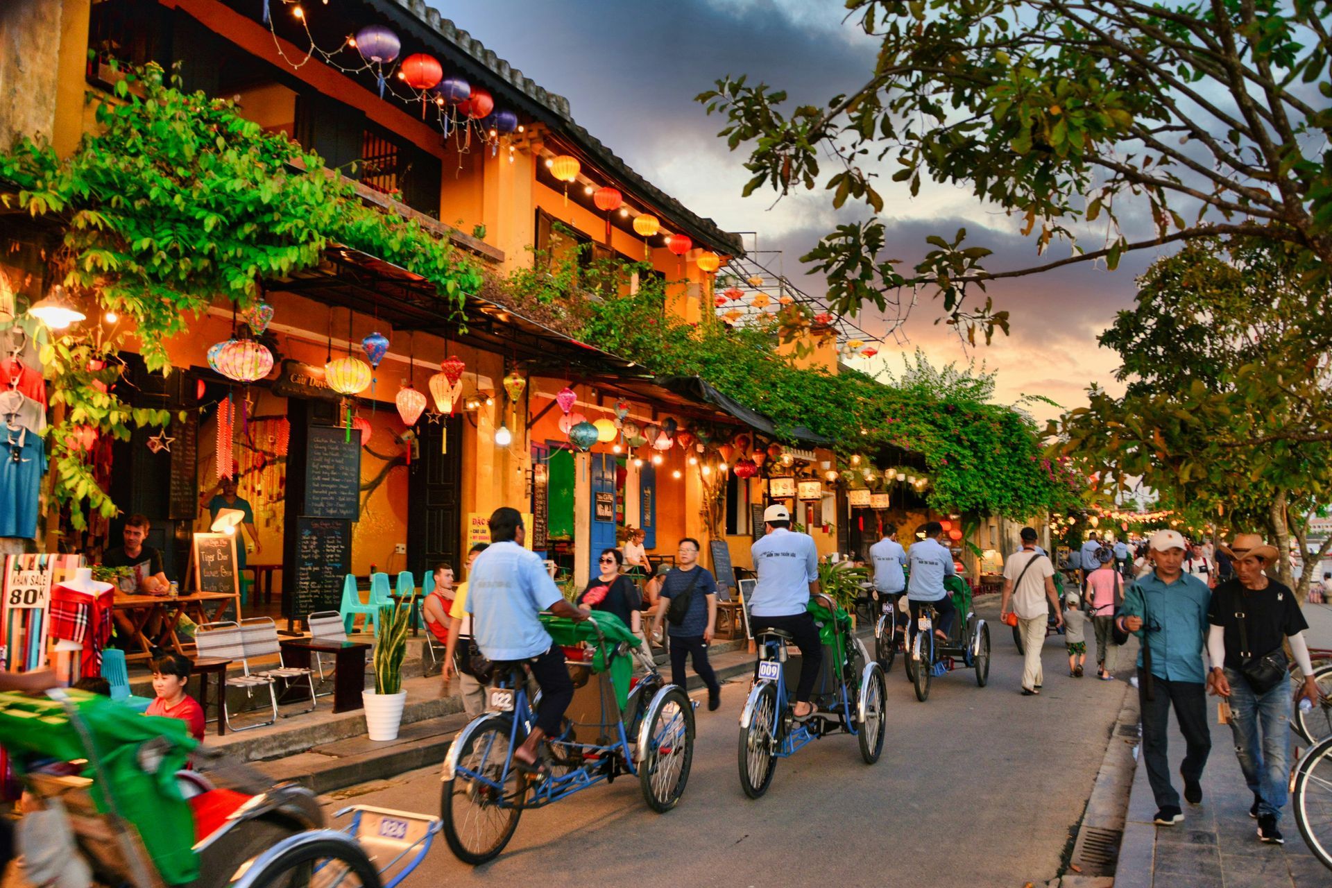 Hoi An, Vietnam street scene with colorful buildings, lanterns, cyclists, and pedestrians.