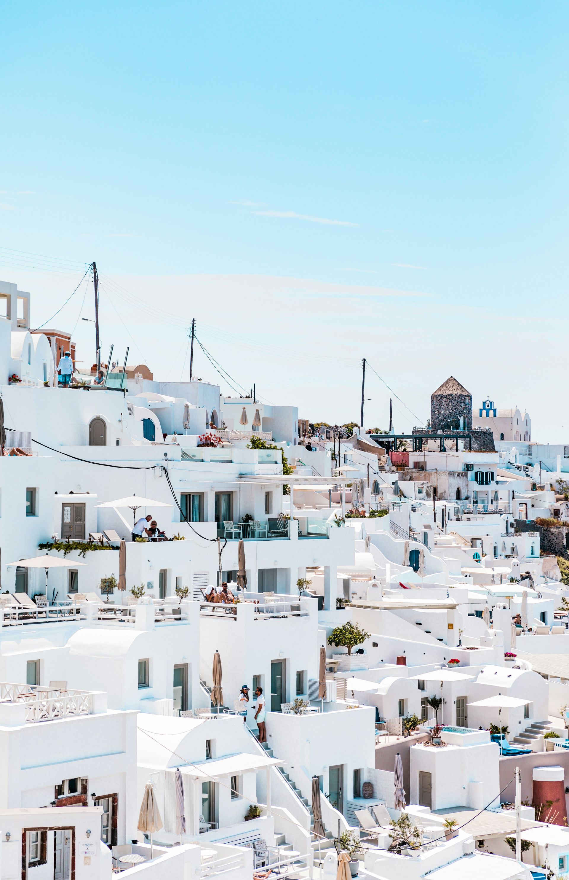 A city with a lot of white buildings and a blue sky in the background in Ios, Greece.