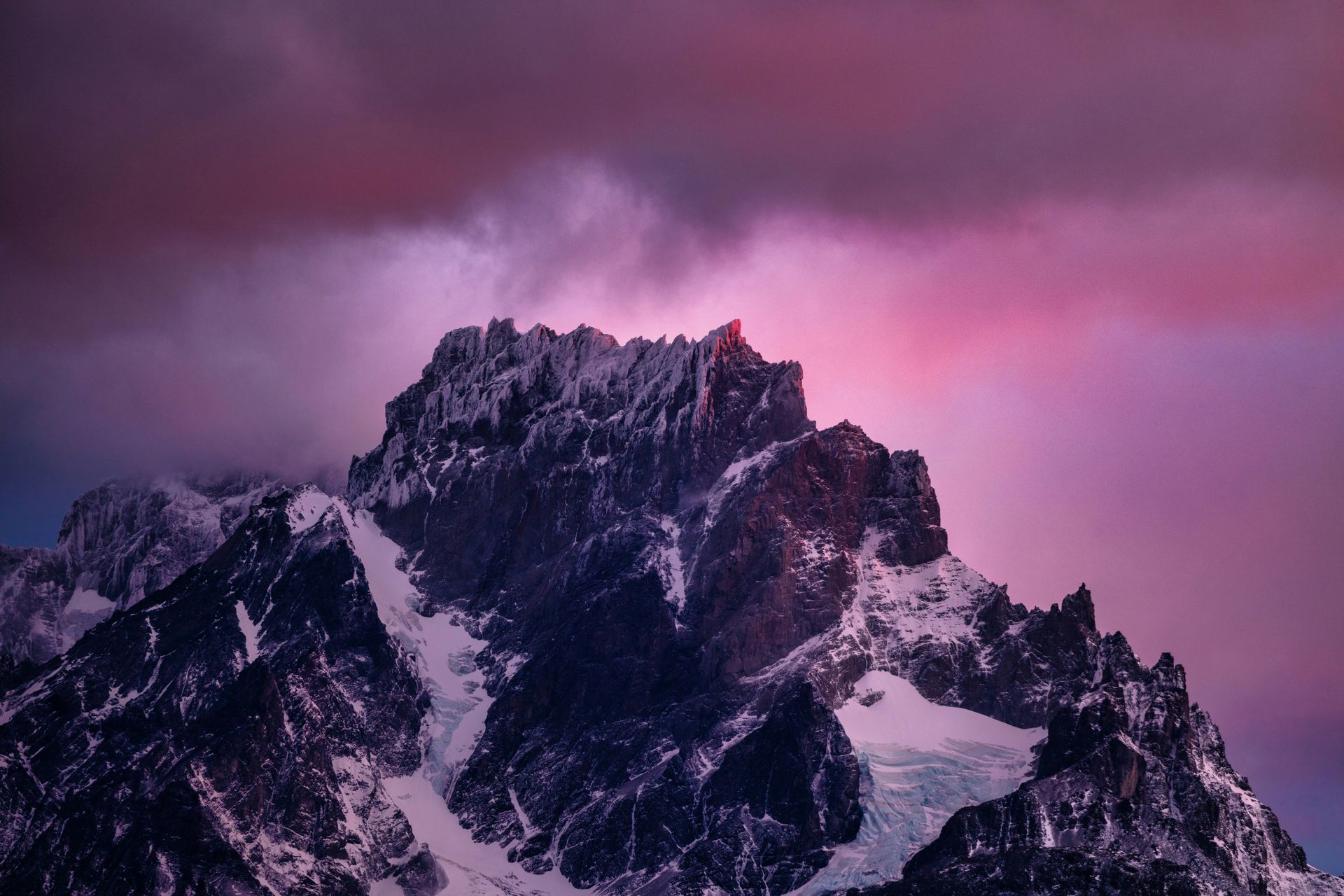 Snow-capped mountain peak against a backdrop of a pink and purple sunset in Patagonia, Chile.