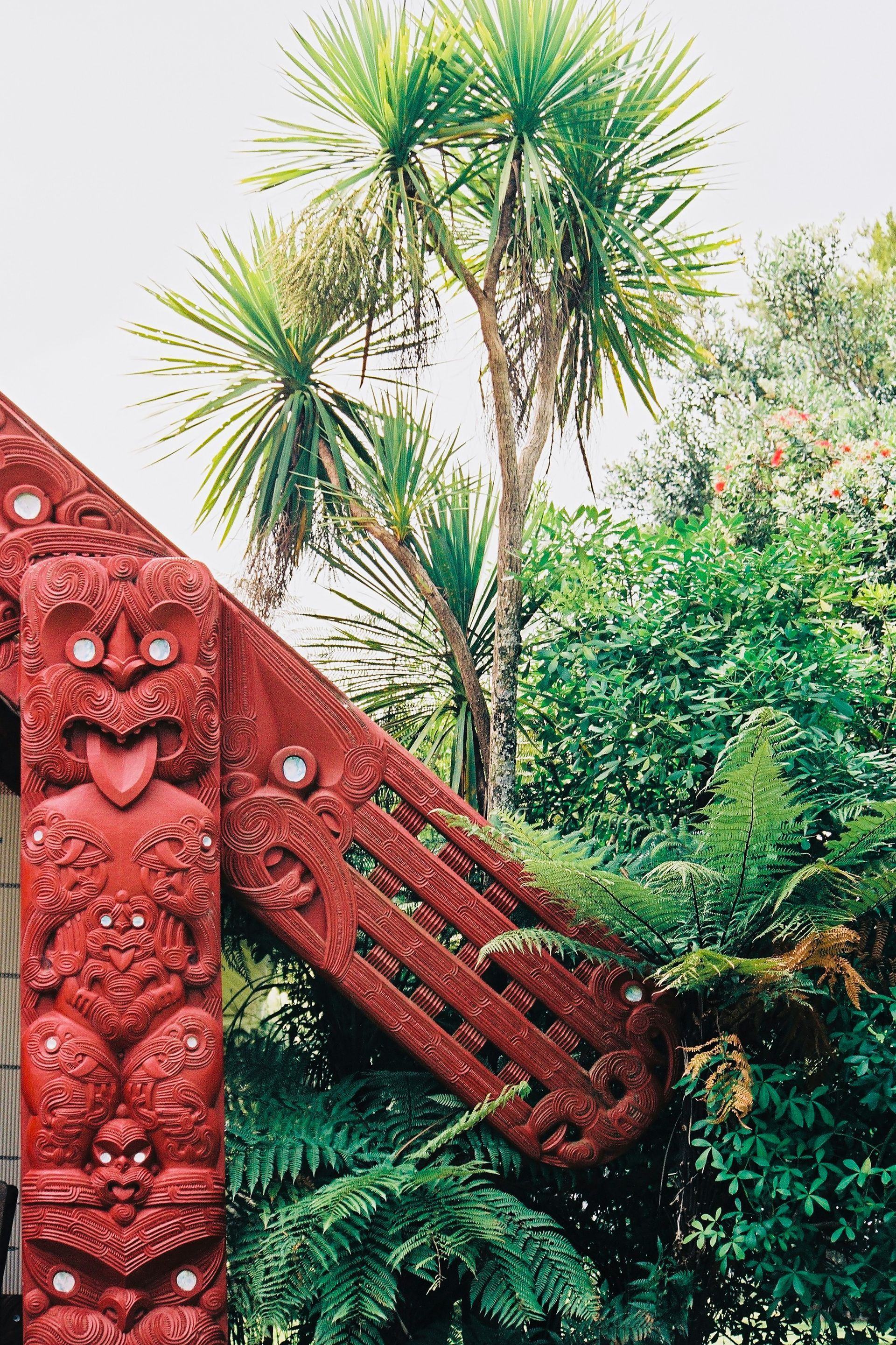 There is a Māori statue of a red man on the side of a building in New Zealand.