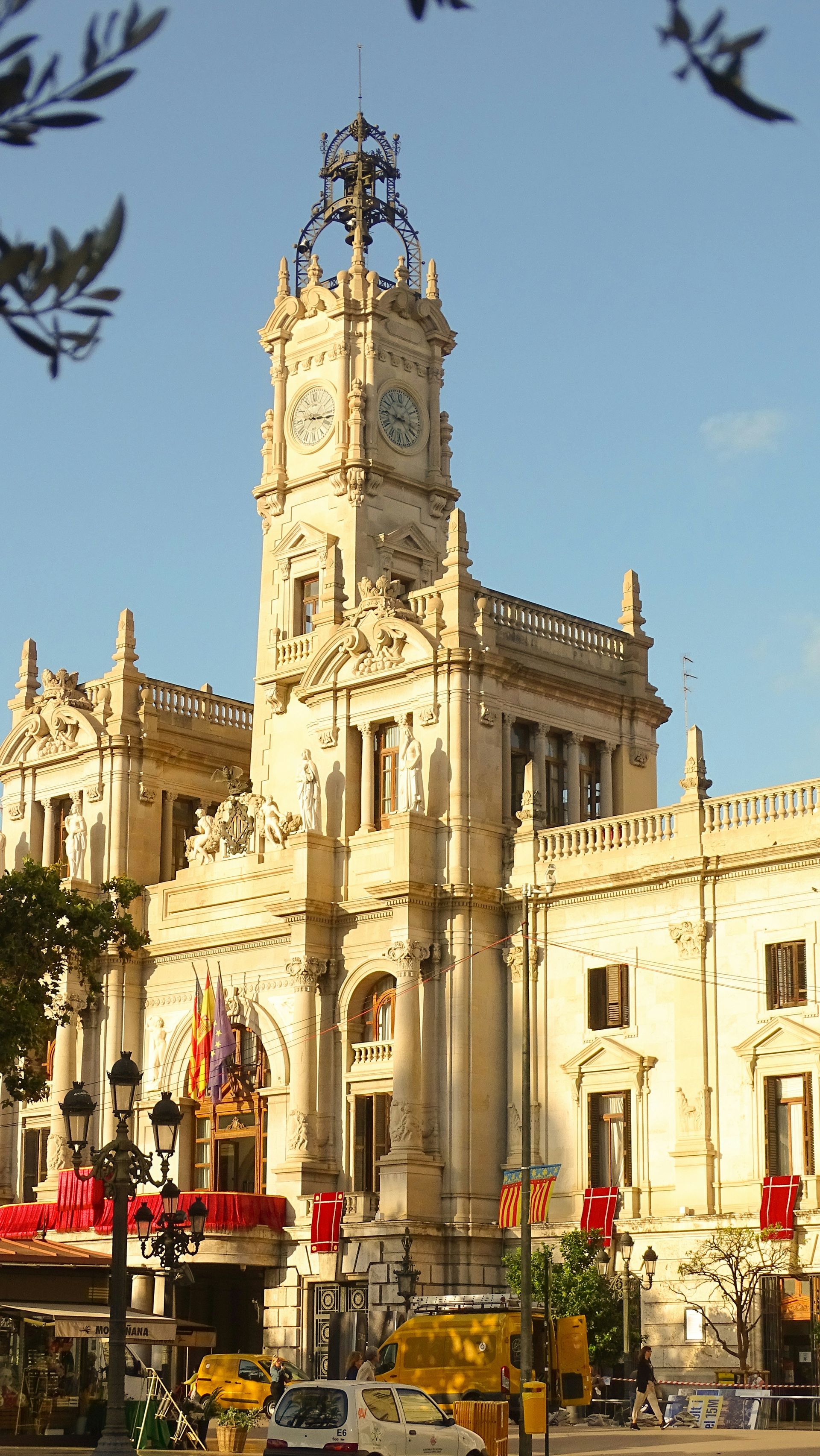 Valencia City Hall, Spain. Ornate beige building with clock tower, flags, and blue sky.