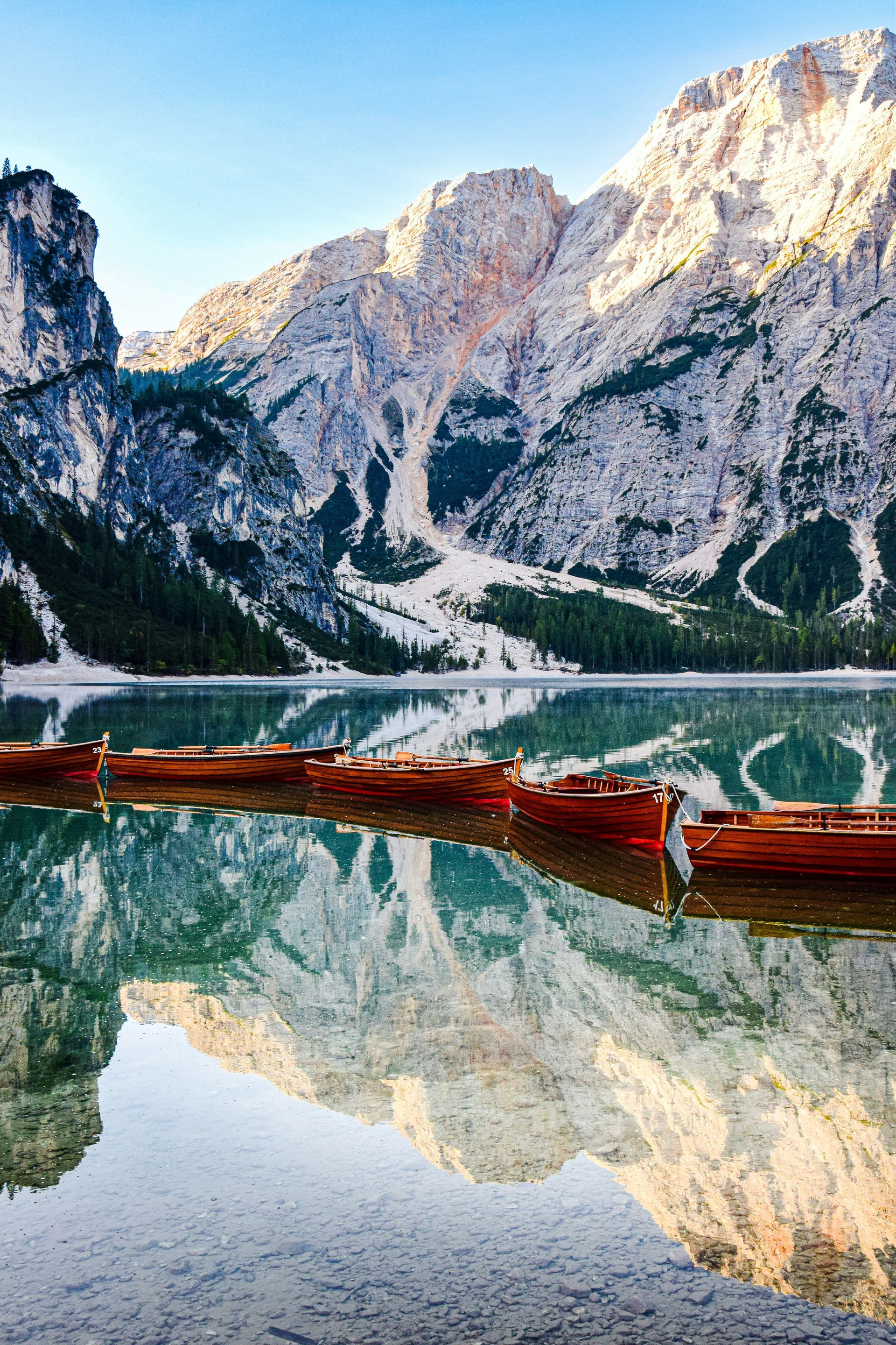 A group of boats are floating on Lake Braies with the Dolomites in the background in Italy.