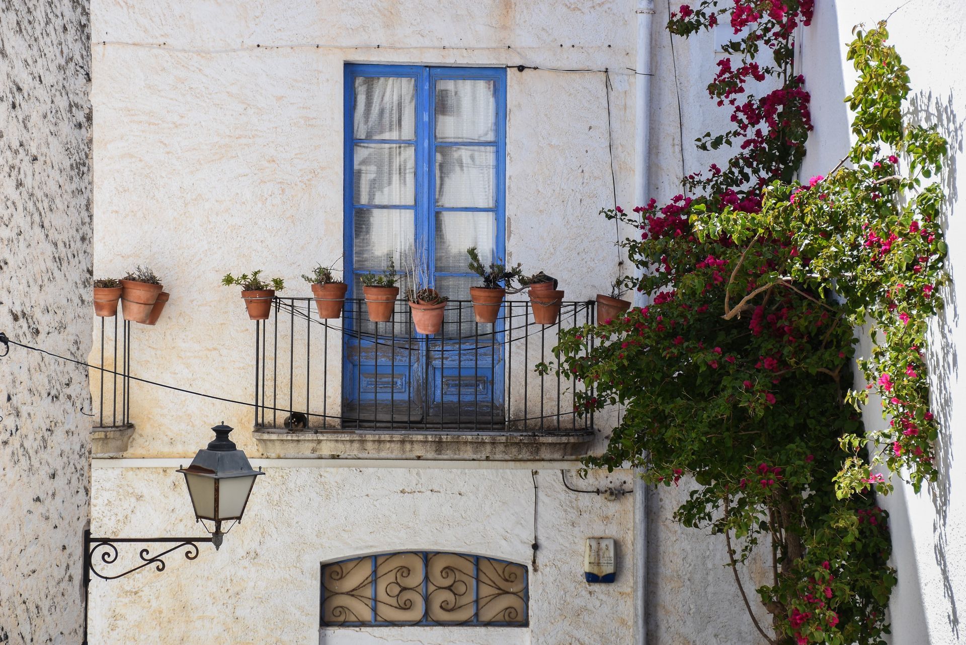 A white building with a balcony and potted plants on it on Costa Brava, Spain.