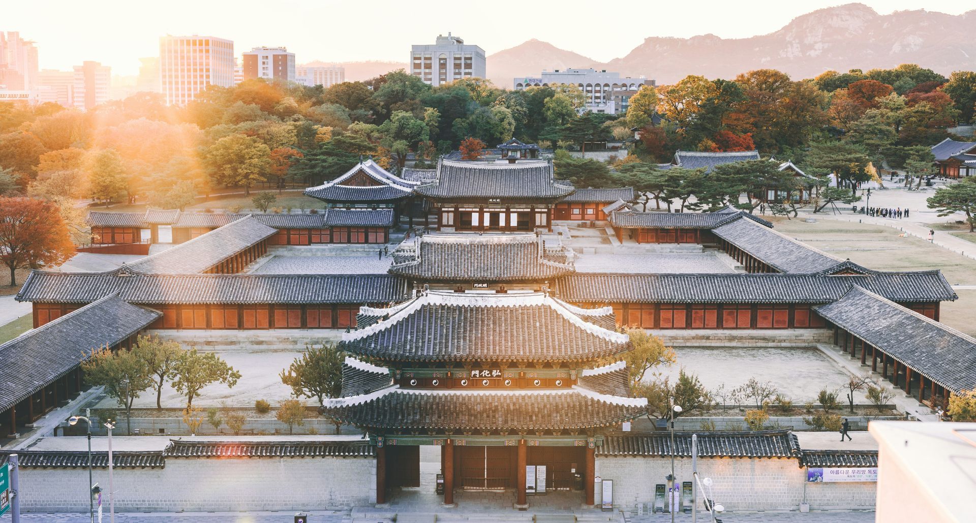 Traditional Korean palace bathed in warm sunlight; buildings with tiled roofs and wooden structures in Seoul, South Korea.