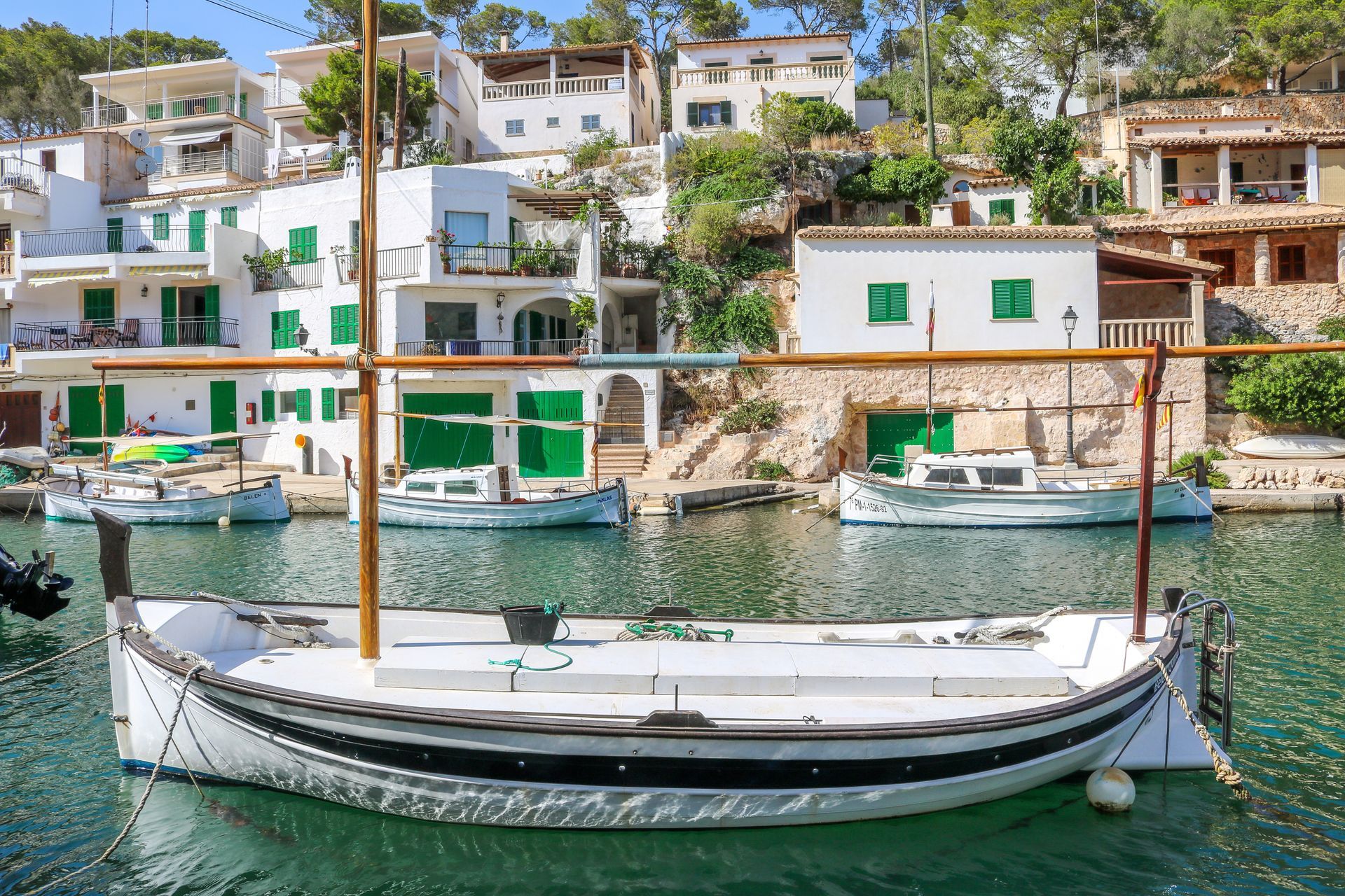 A boat is docked in a harbor with buildings in the background in Mallorca, Spain.
