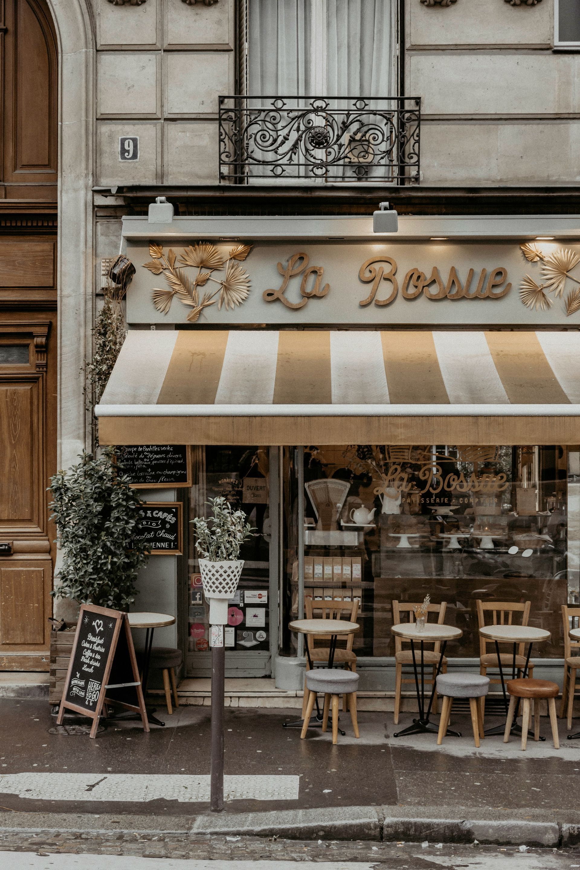 A restaurant with tables and chairs under a striped awning in Paris, France.