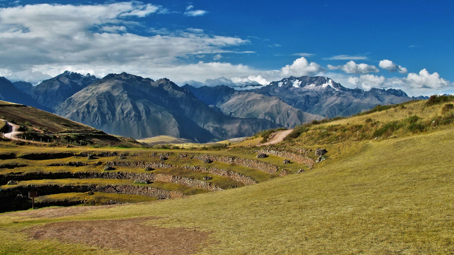 A lush green field with mountains in the background in the Sacred Valley of Peru.