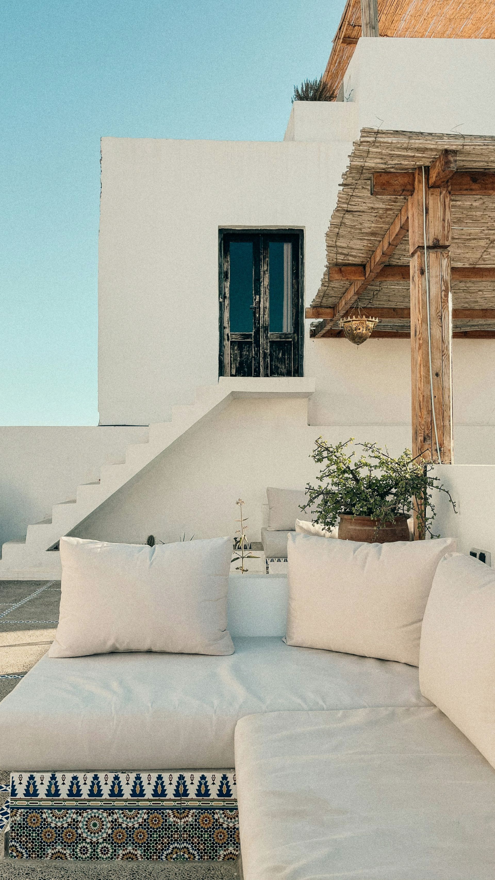 A white couch with white pillows is in front of a white building in Taghazout, Morocco.