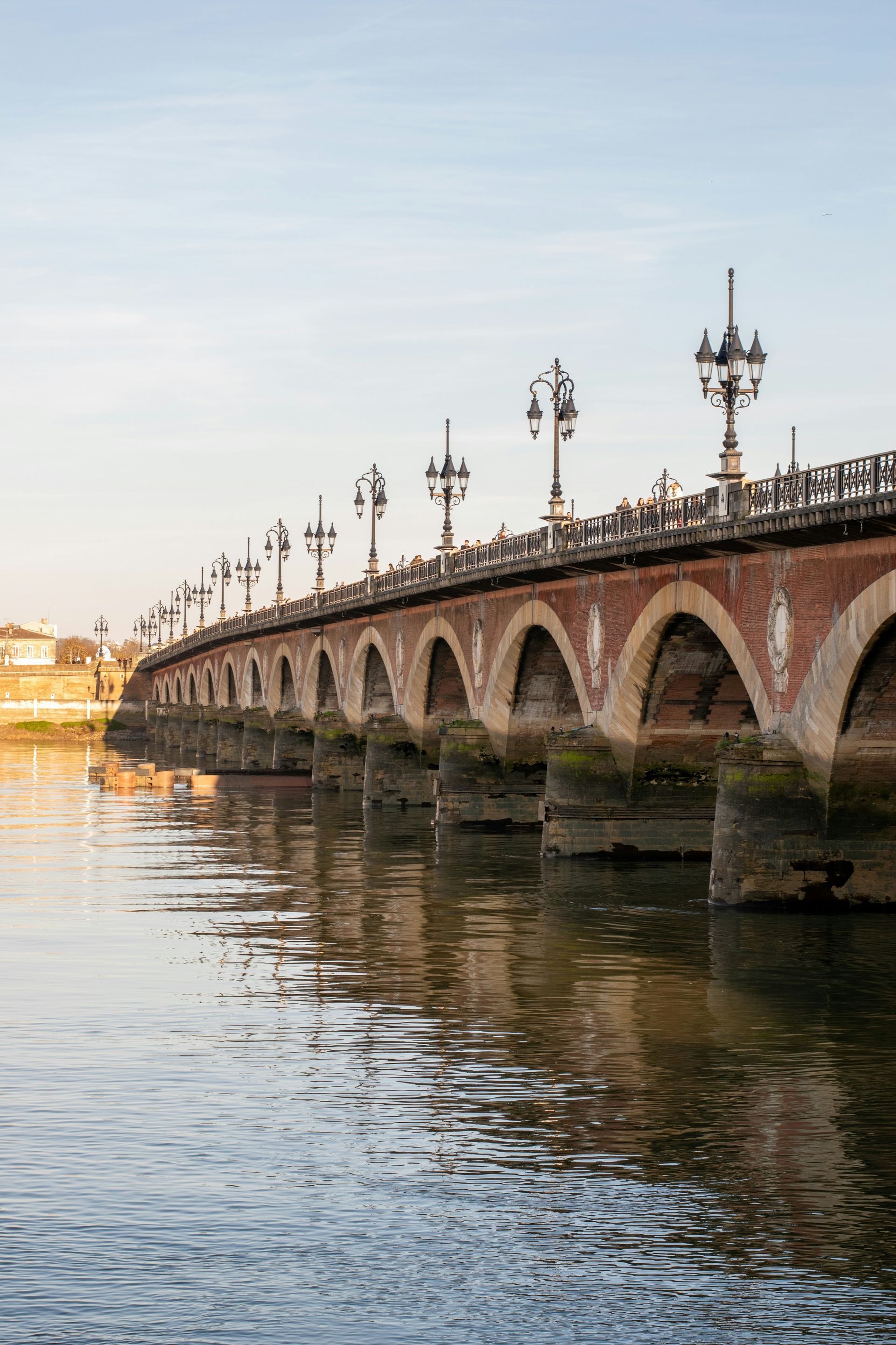 A bridge over a body of water with a lot of lights on it in Bordeaux, France.