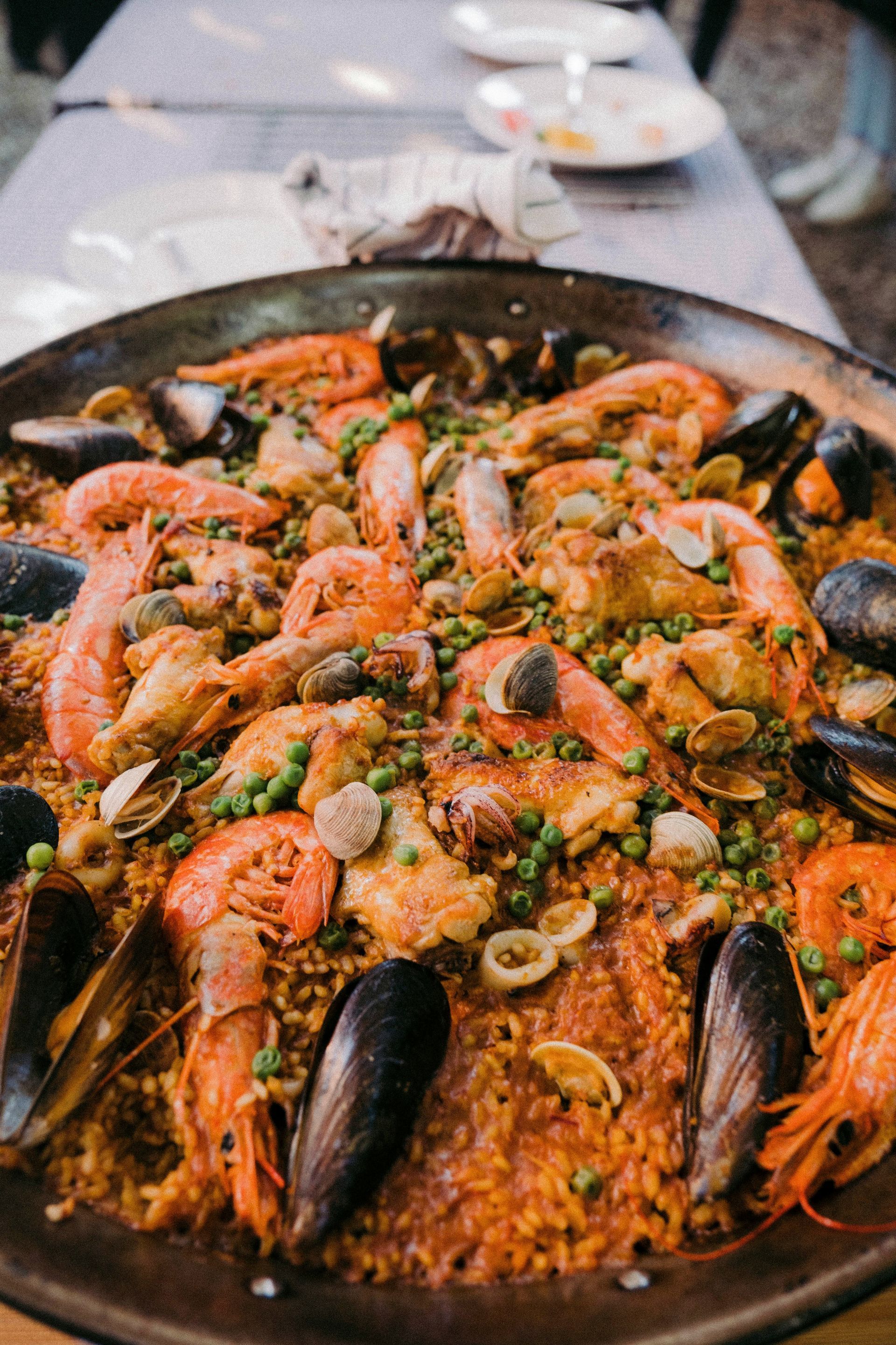 Paella with shrimp, mussels, peas, and other seafood in a large pan in Spain.