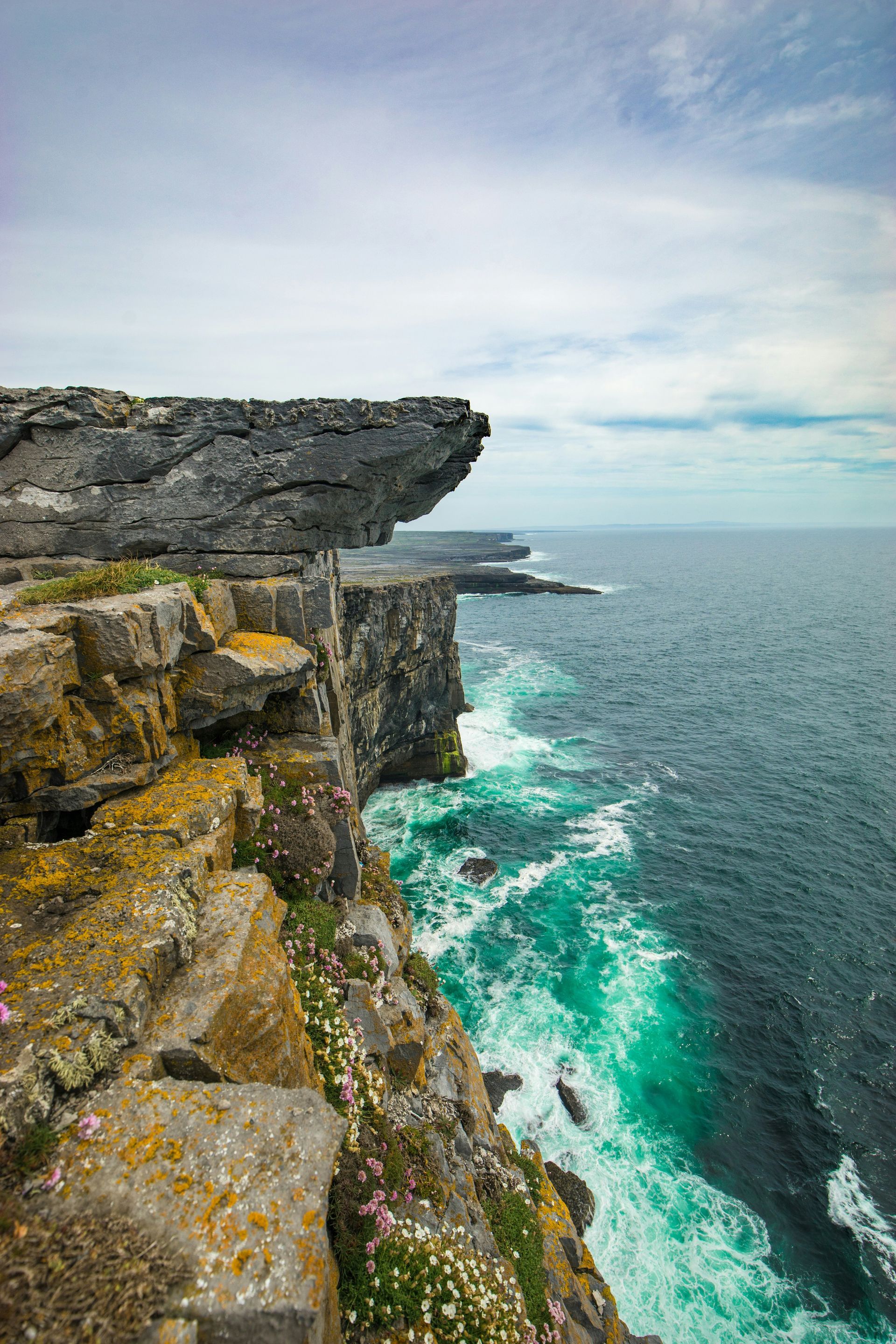 Rocky cliff edge overlooking turquoise ocean on the Aran Islands, Ireland.