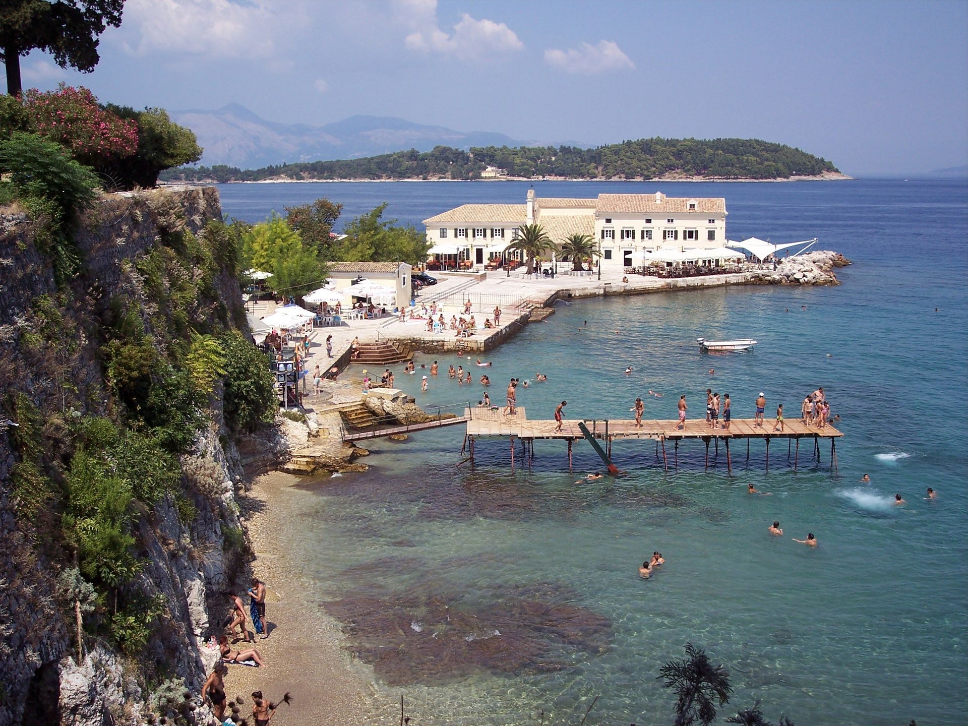 A group of people are swimming in the ocean near a dock in Corfu, Greece