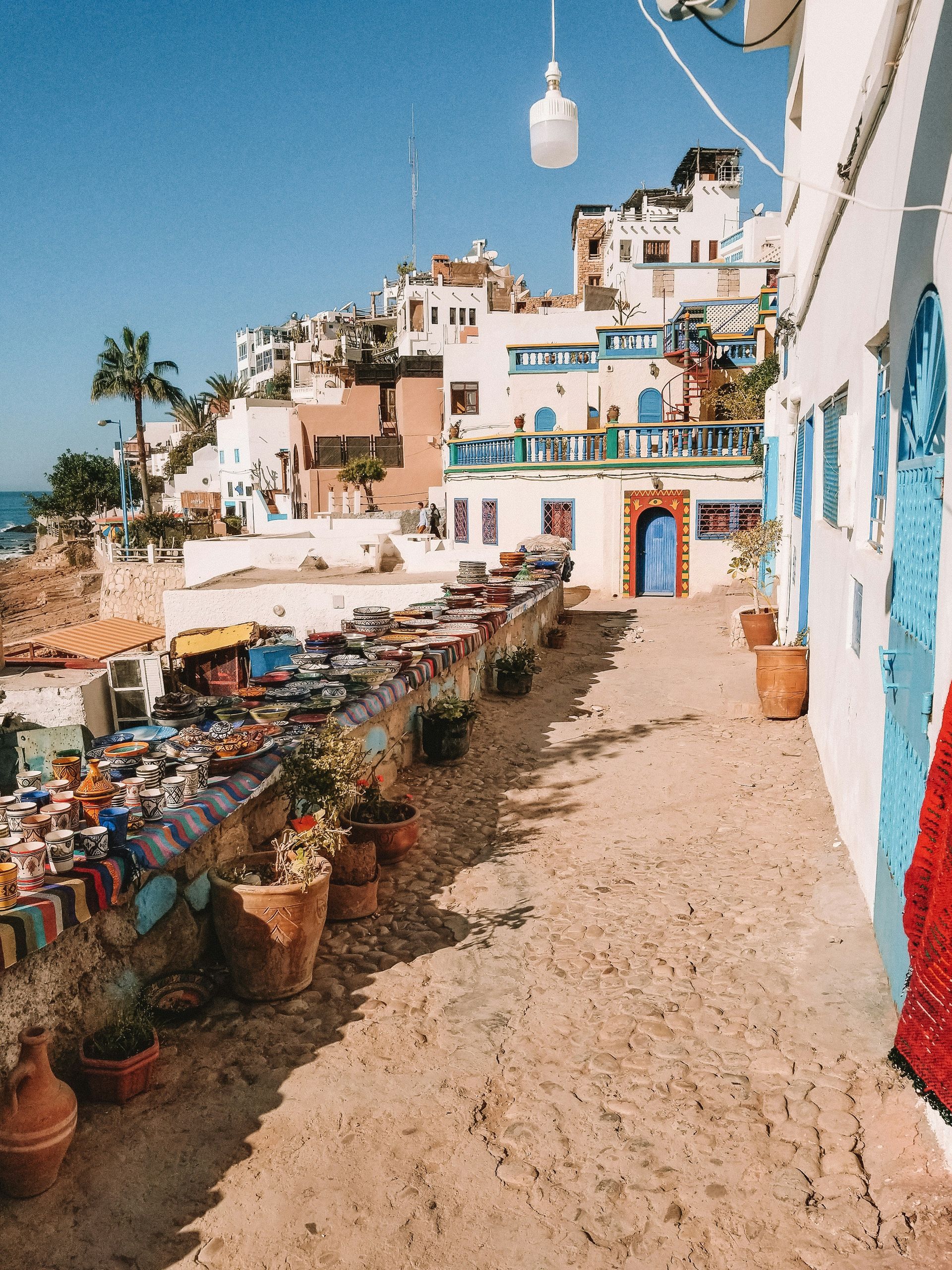 A row of potted plants are lined up in front of a building in Taghazout, Morocco.