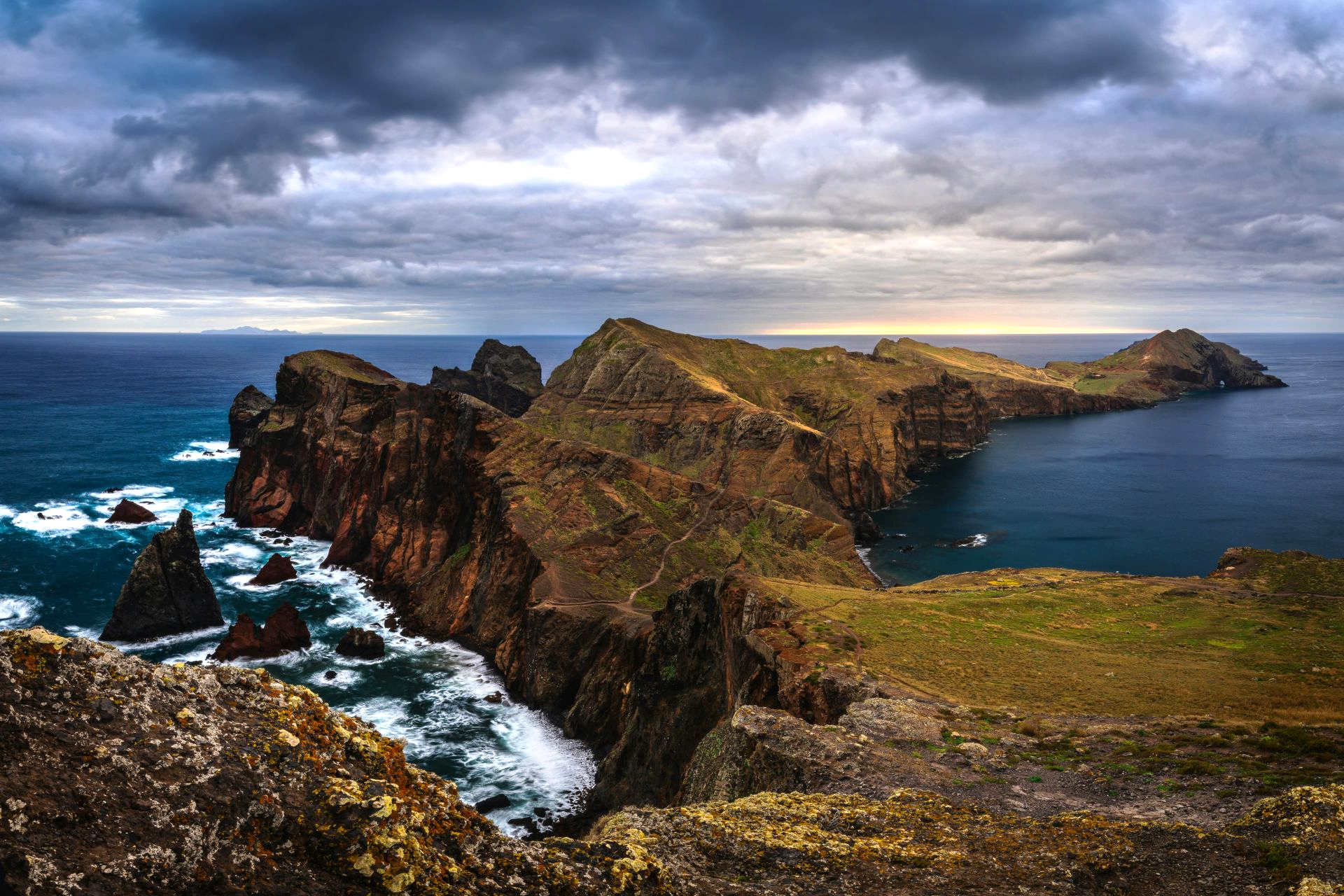 Rocky coastal peninsula jutting into the ocean under a cloudy sky on the island of Madeira, Portugal.
