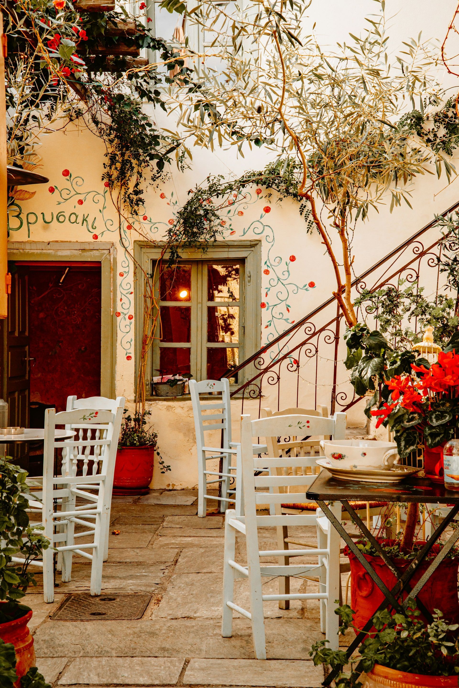 A patio with tables and chairs in front of a building in Athens, Greece.