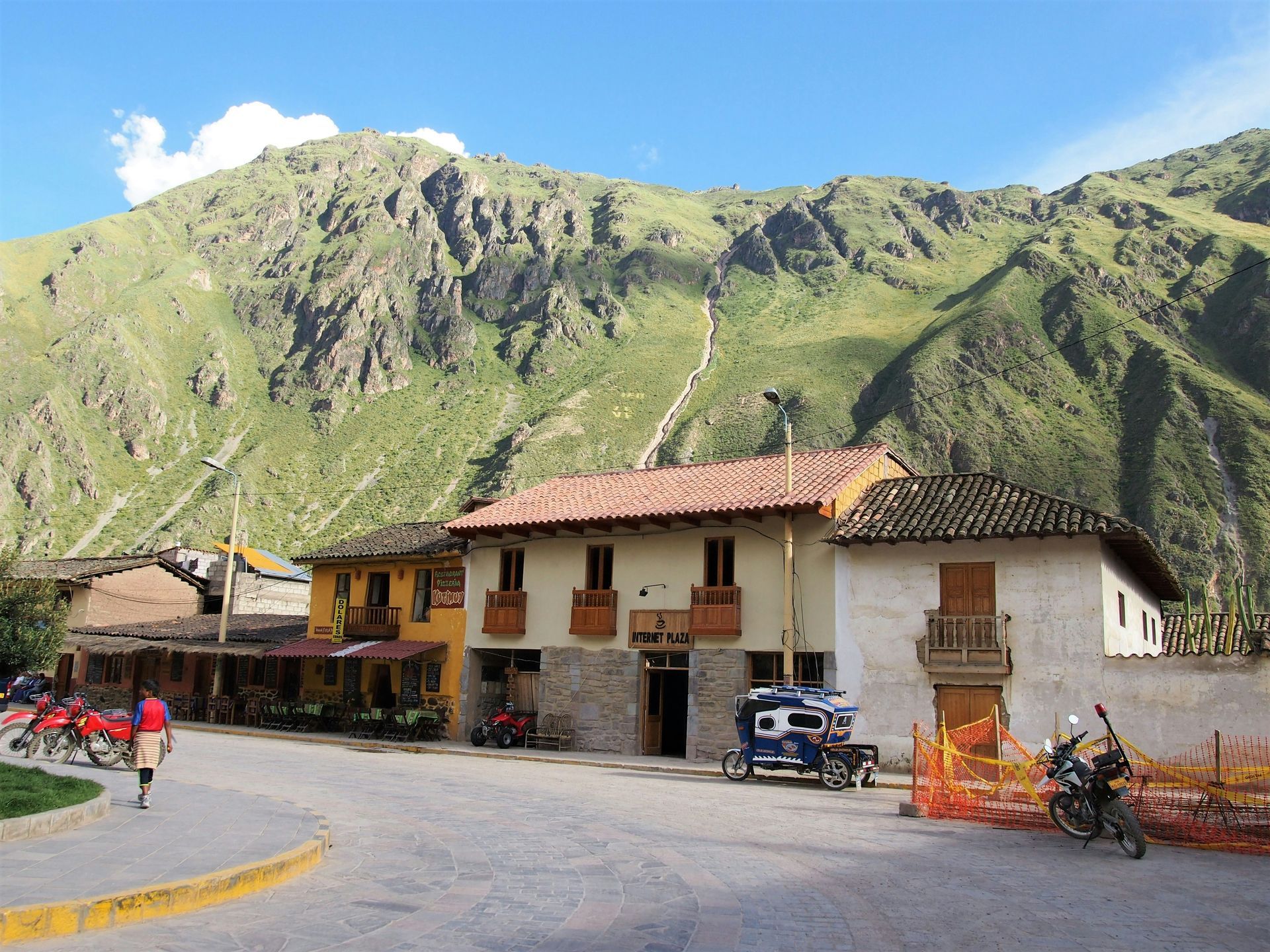 A motorcycle is parked in front of a building with a mountain in the background in the Sacred Valley of Peru.