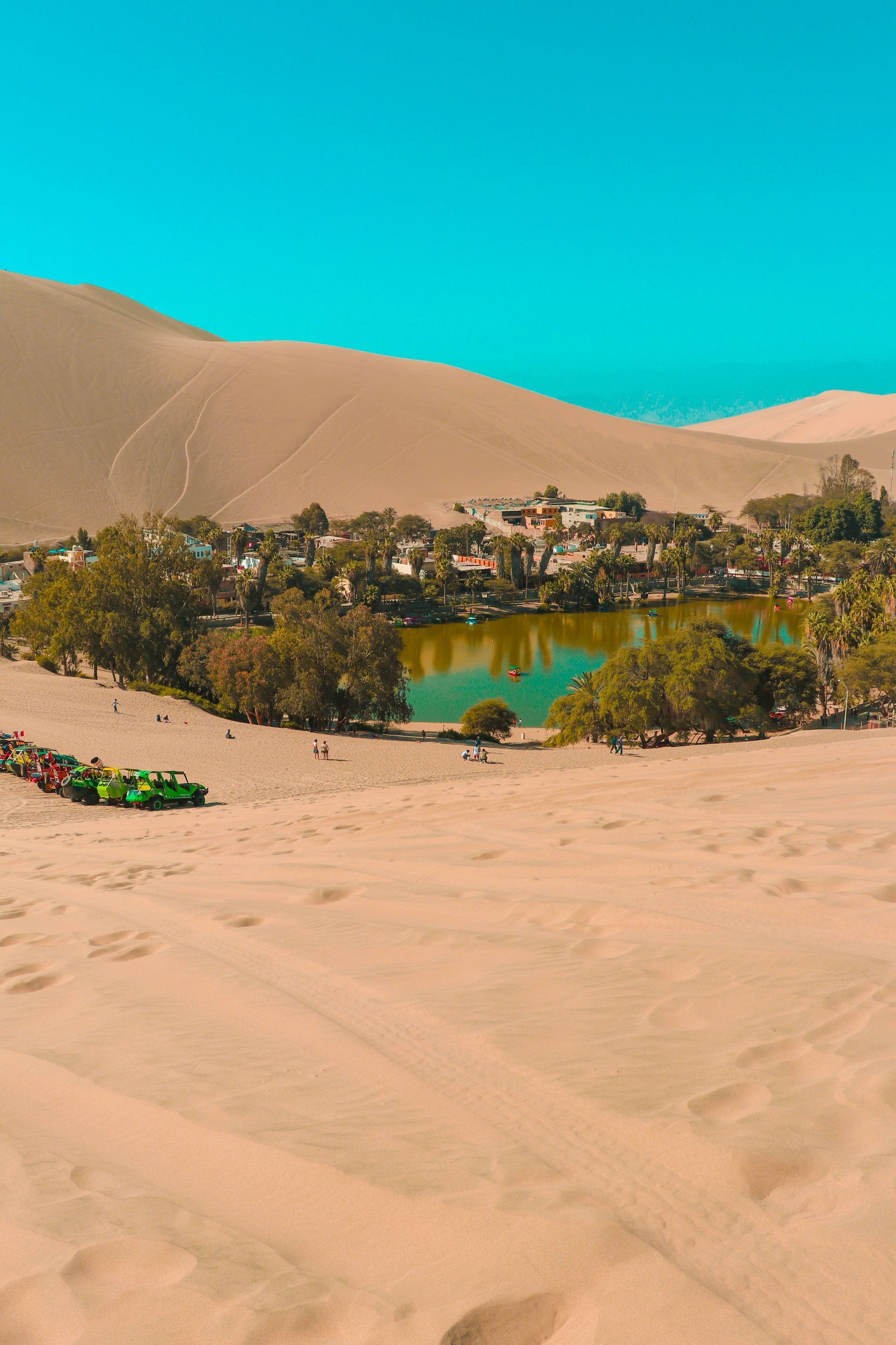 There is a lake in the middle of the desert surrounded by the village of Huacachina, Peru.