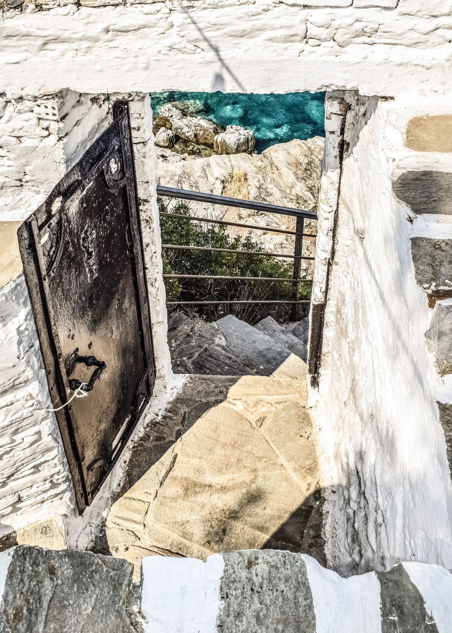 A doorway leading to a staircase with a view of the ocean in Skopelos, Greece.