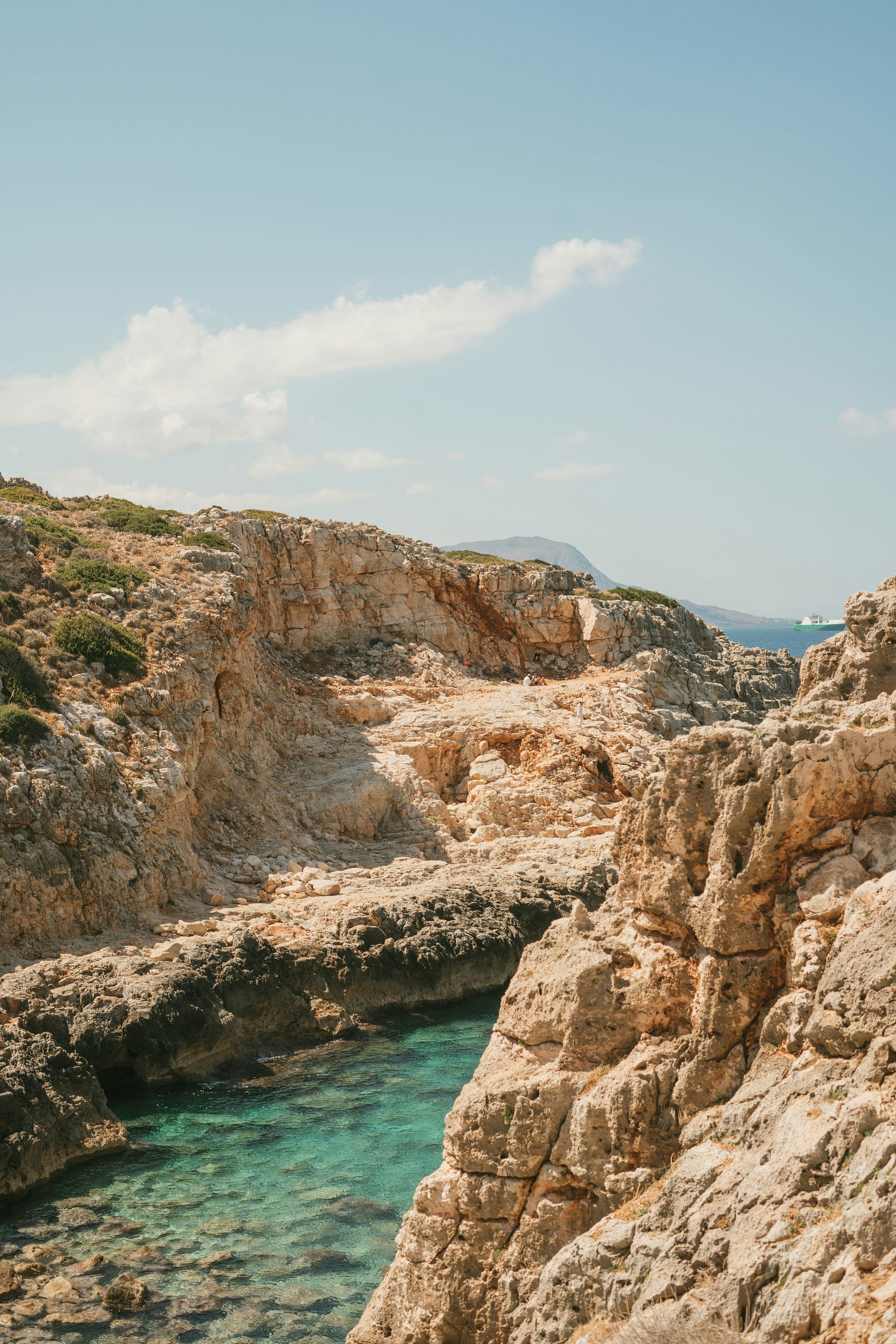 A view of a rocky cliff overlooking a body of water in Crete, Greece.