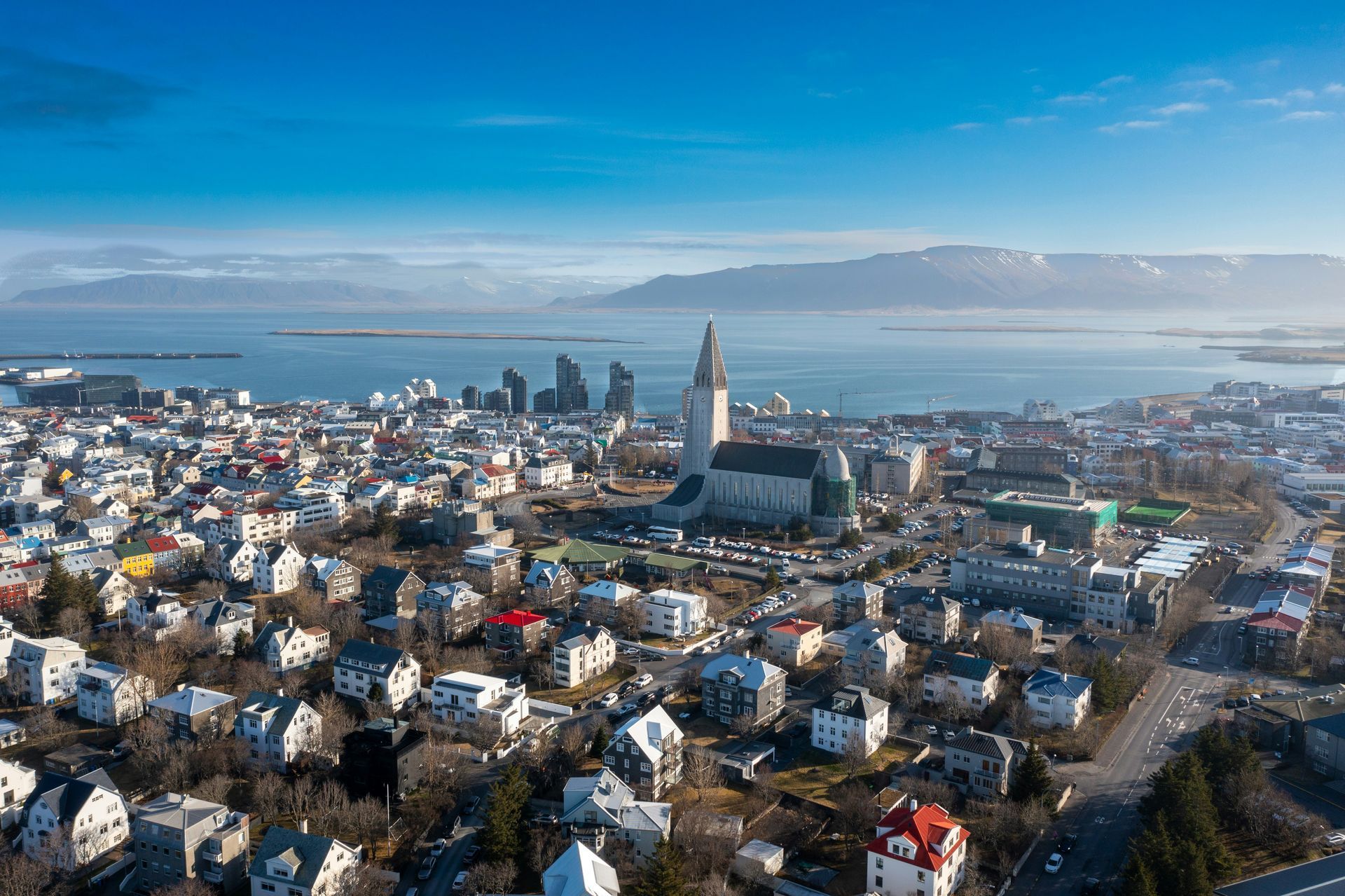 Reykjavik, Iceland, aerial view of a city with Hallgrímskirkja church and a harbor under a blue sky.