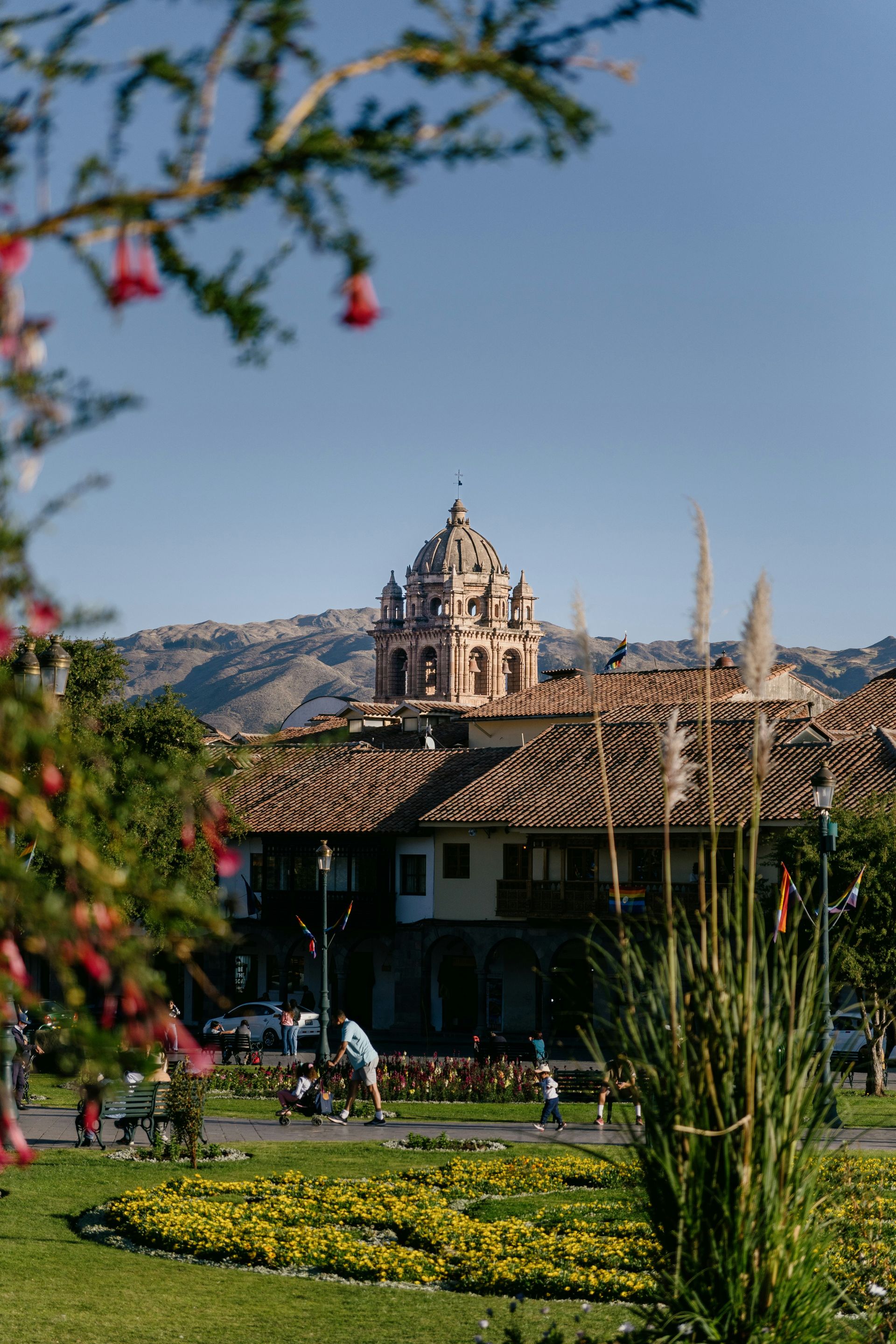 A large building with a dome on top of it is sitting in the middle of a park in Cusco, Peru.