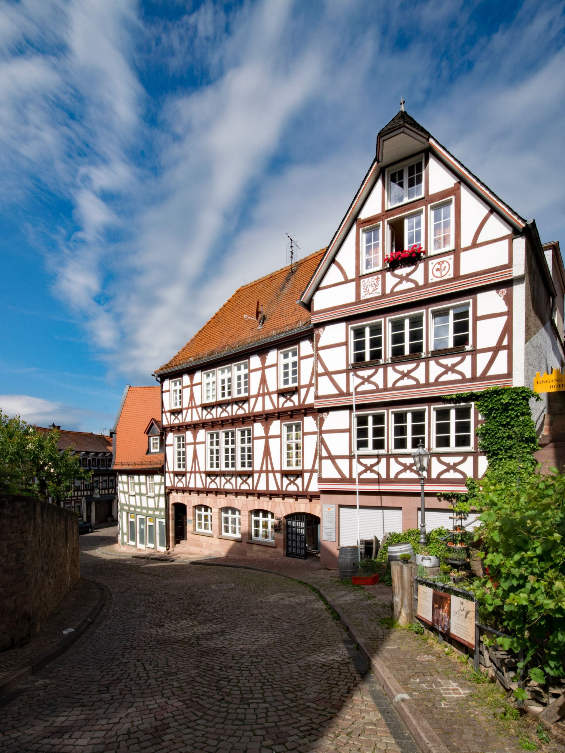A large white and brown building with a blue sky in the background in Gelnhausen, Germany.