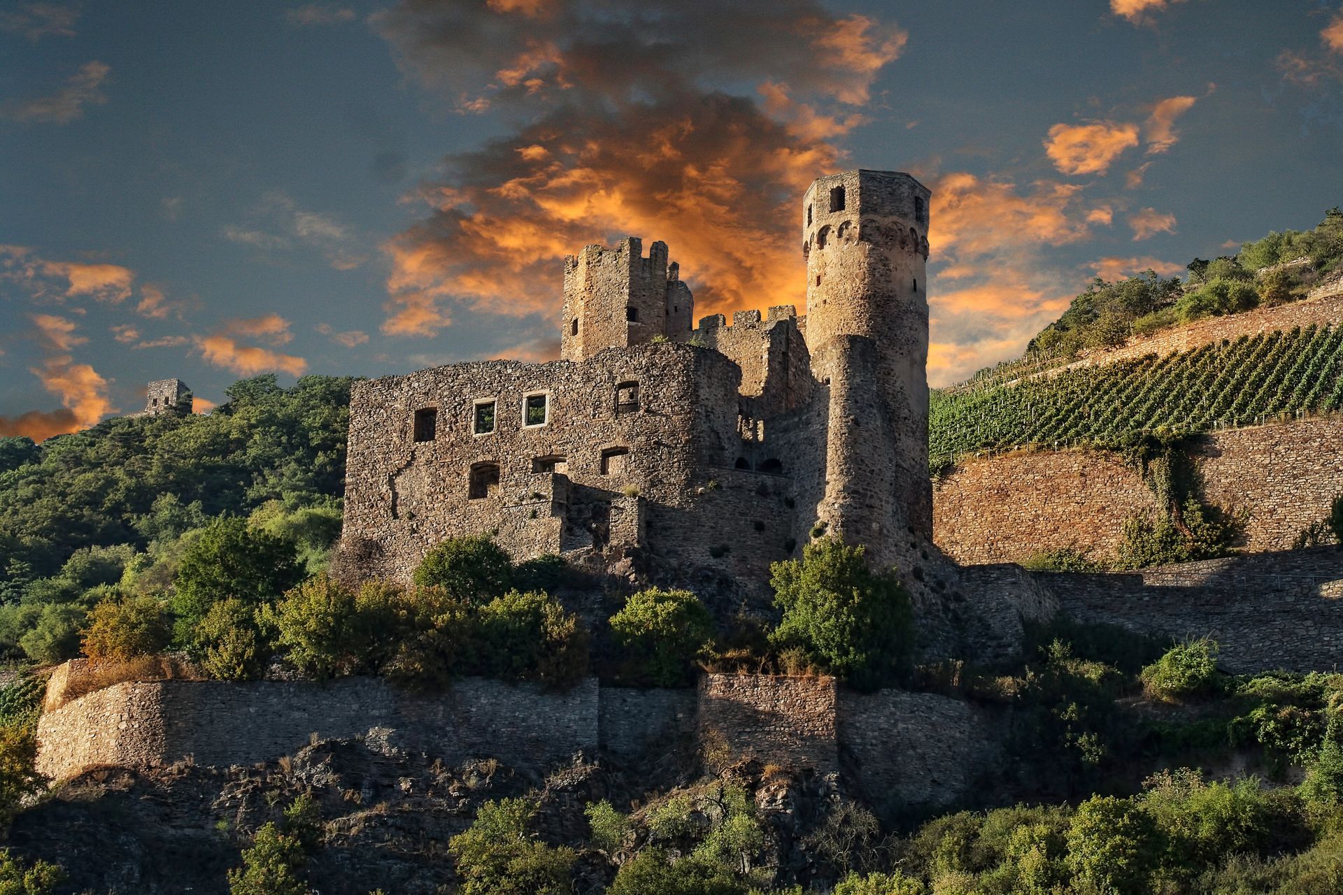 A castle on top of a hill with a sunset in the background in the Rhine Valley.