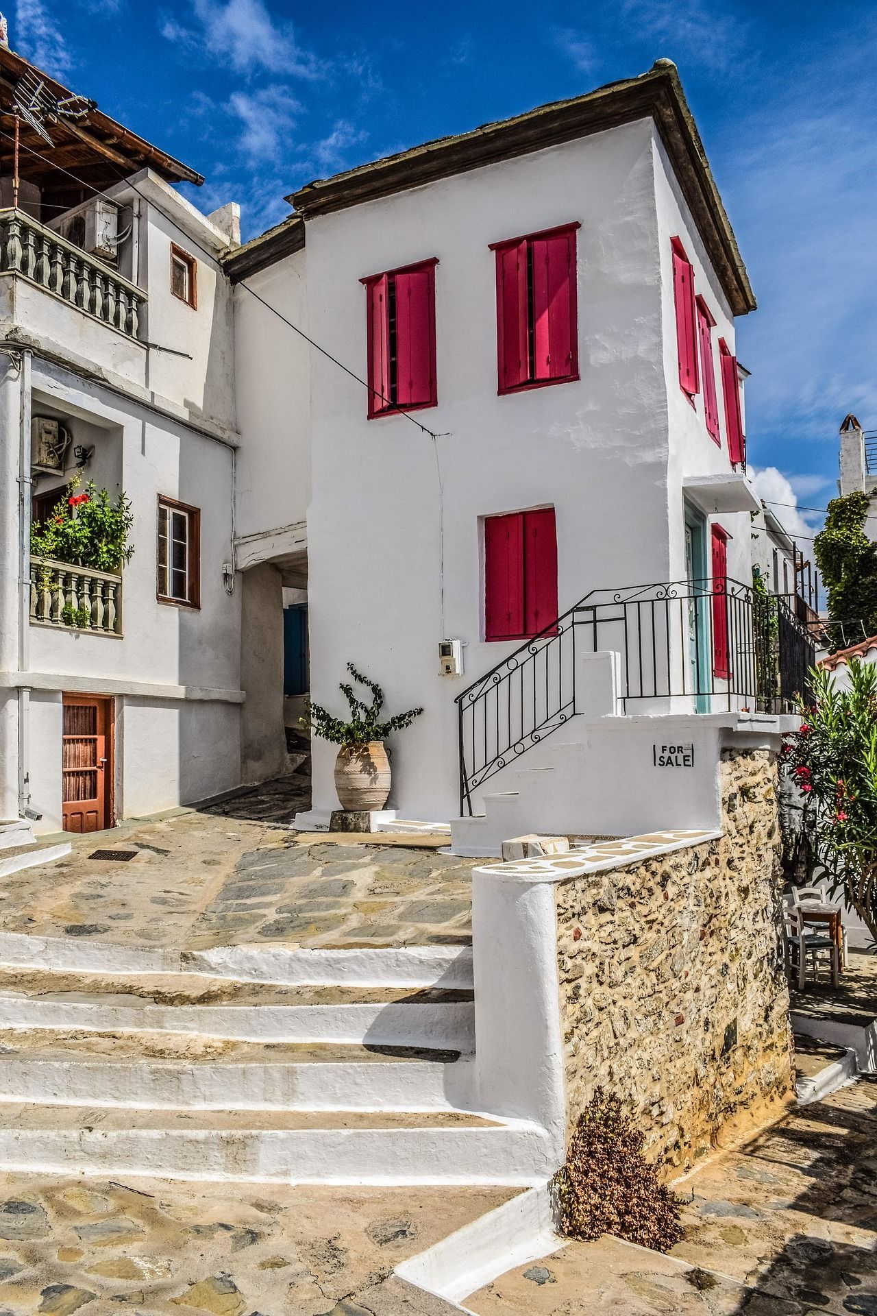 A white house with pink windows and stairs in a small town in Skopelos, Greece.