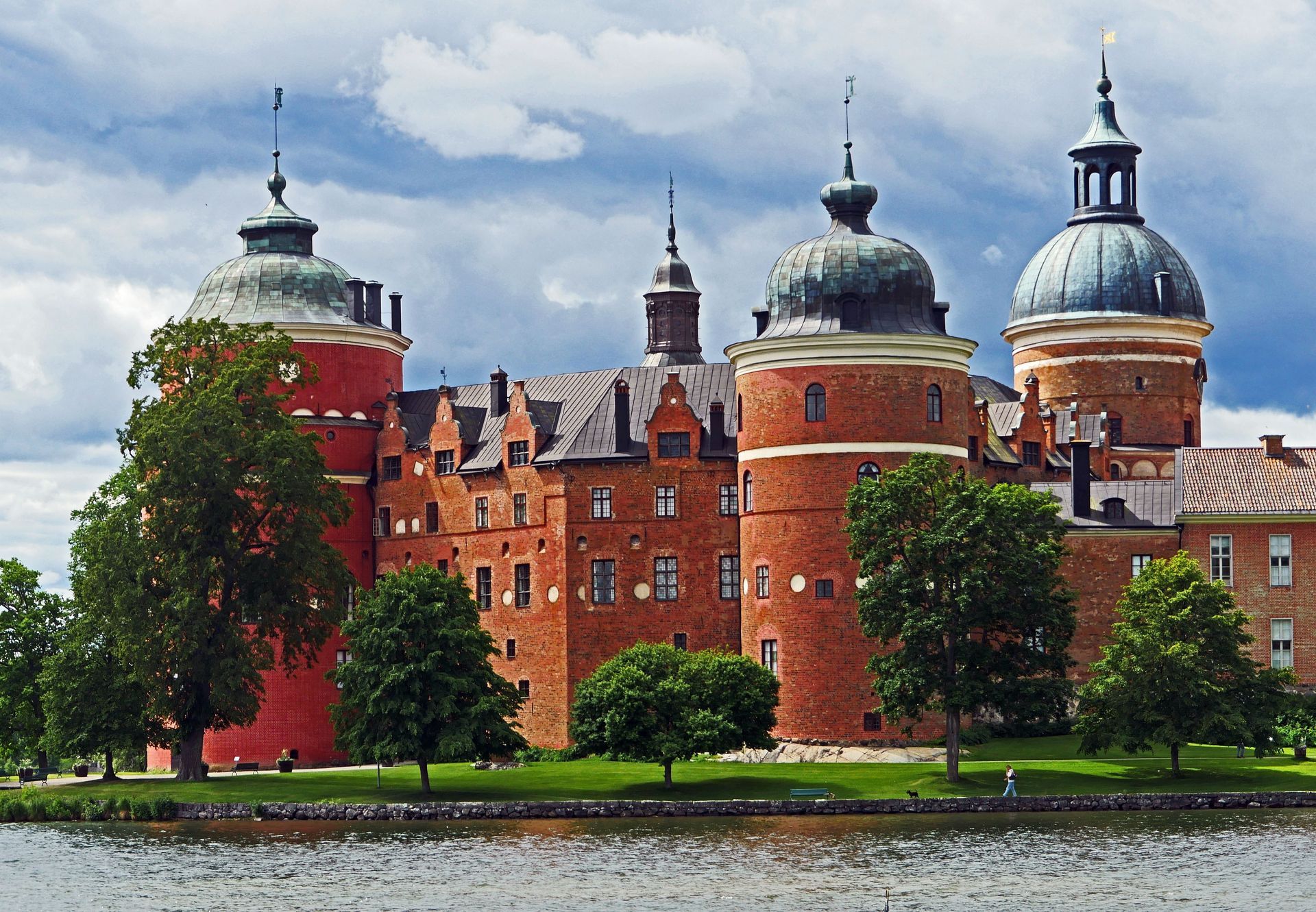 A large red brick castle sits on the shore of lake Mälaren in Stockholm.