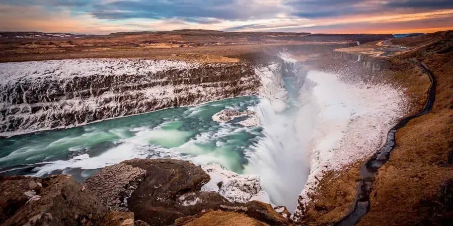 An aerial view of a waterfall in iceland at sunset.