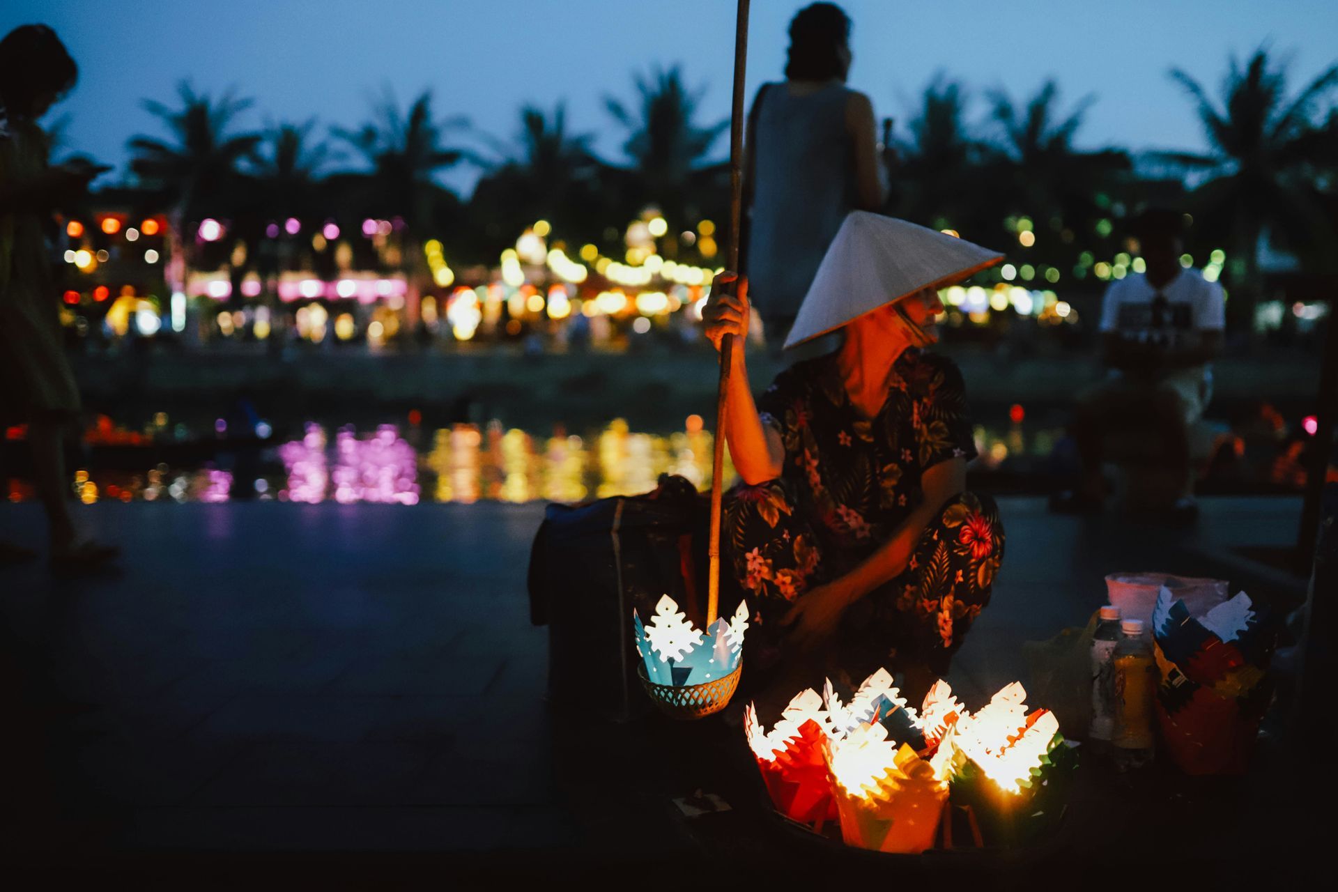 Woman selling glowing paper lanterns at night, Hoi An, Vietnam.