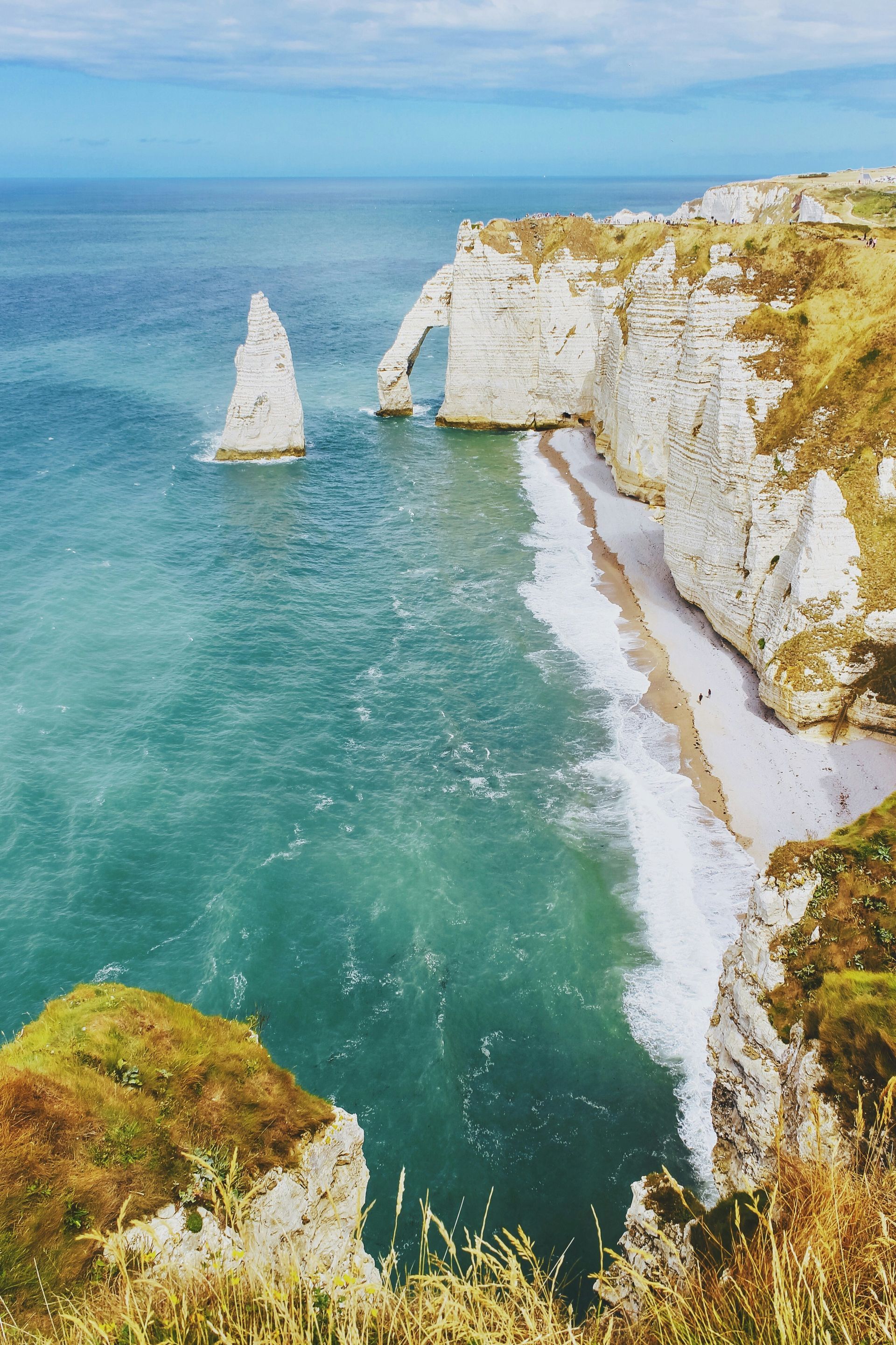 The ocean is surrounded by cliffs at Étretat beach in Normandy, France.