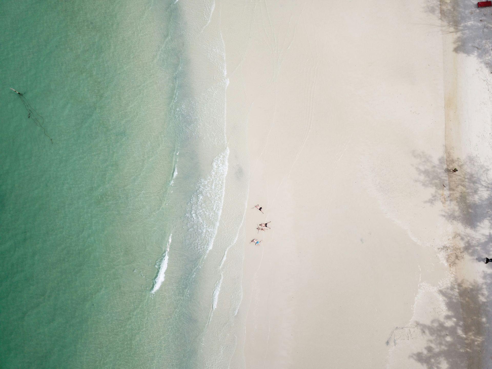 Aerial view of a beach with turquoise water meeting a sandy shore; in Koh Rong, Cambodia.