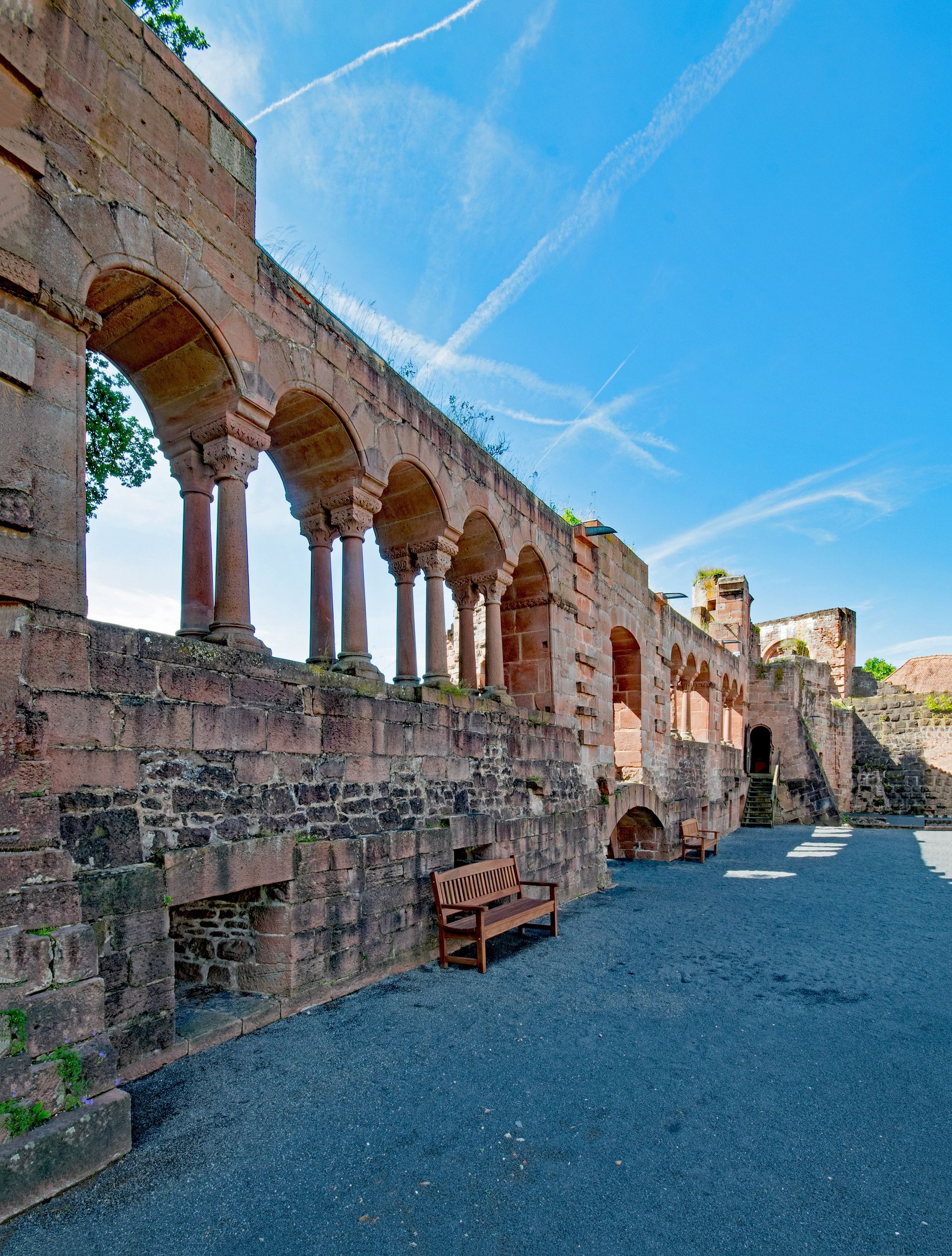 A stone wall with arches and a bench in front of it in Gelnhausen, Germany.