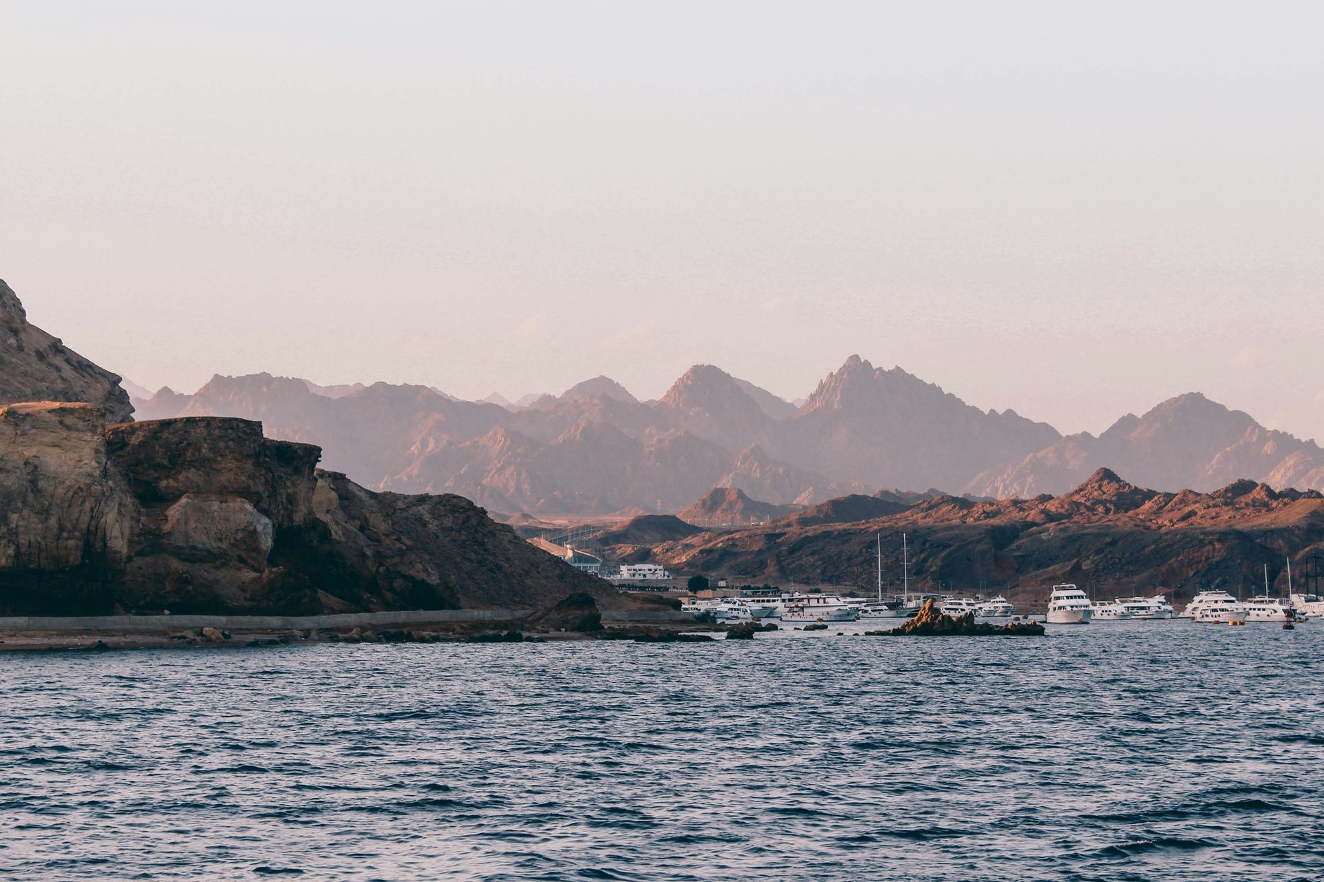 A body of water with mountains in the background and boats in the foreground in Sharm El-Sheikh, Egypt.