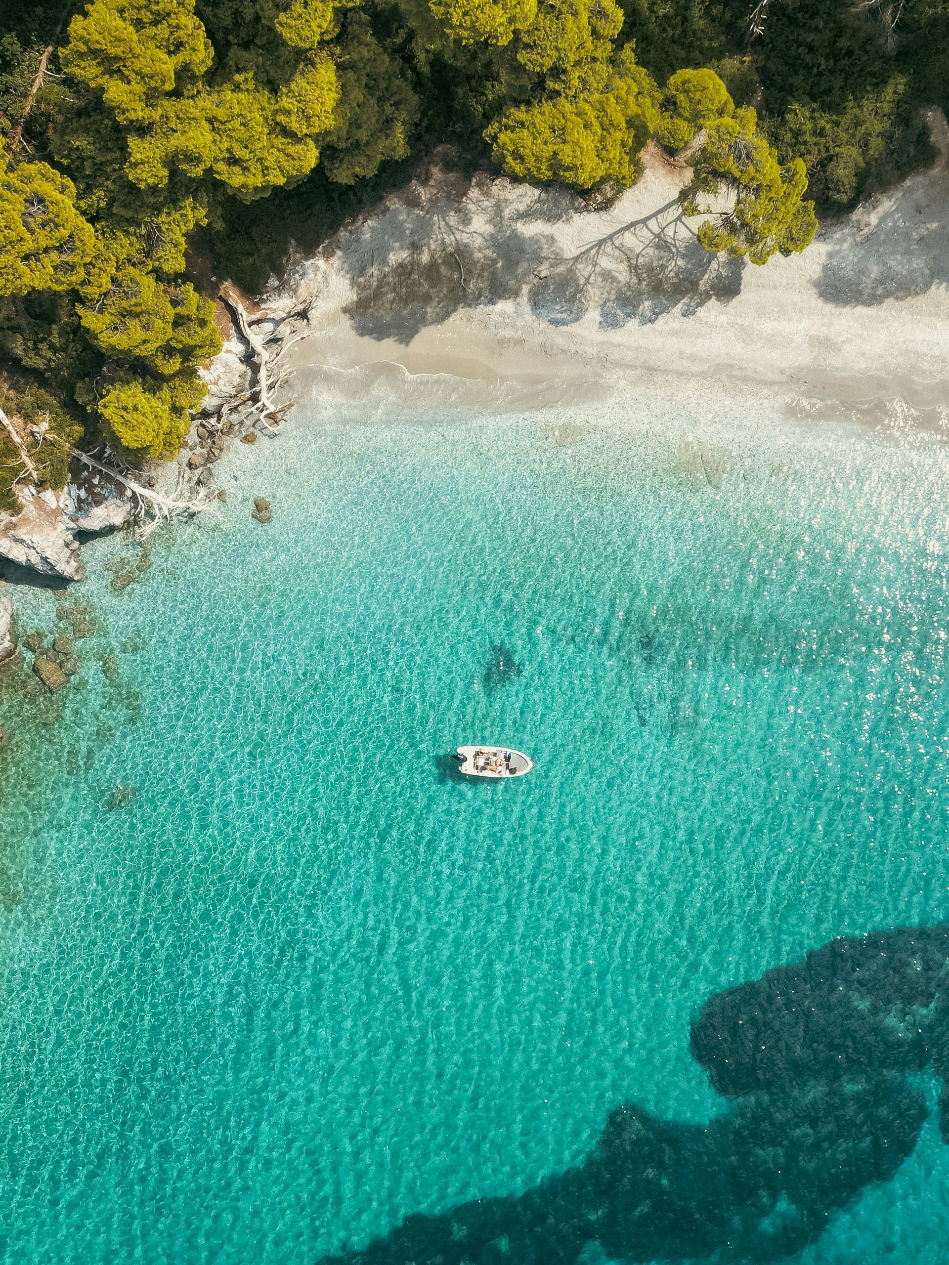 An aerial view of a beach with a boat in the water in Skopelos, Greece.