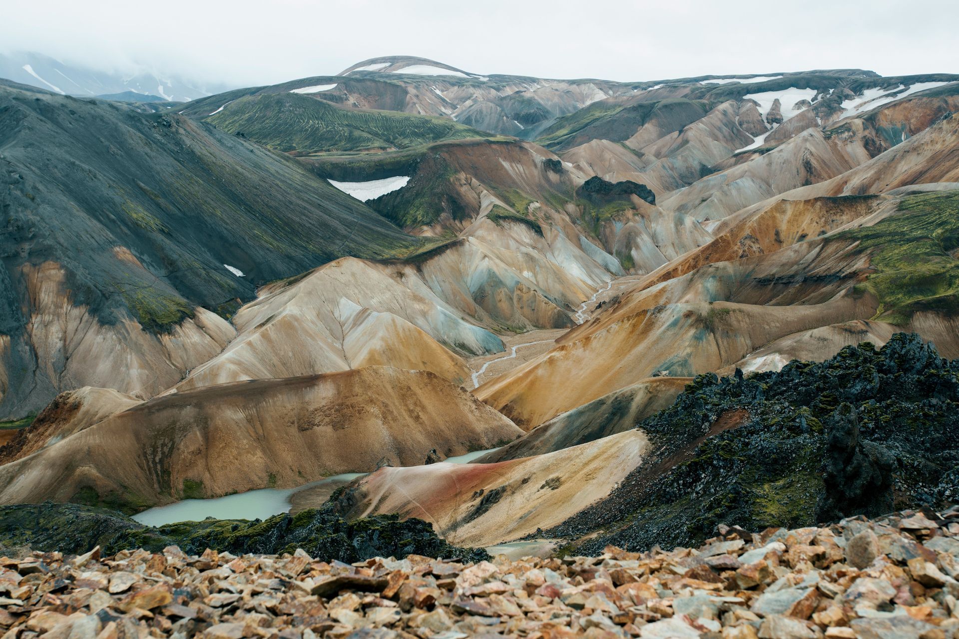 Colorful, rugged landscape of hills and valleys in Landmannalaugar, Iceland. Small turquoise ponds.