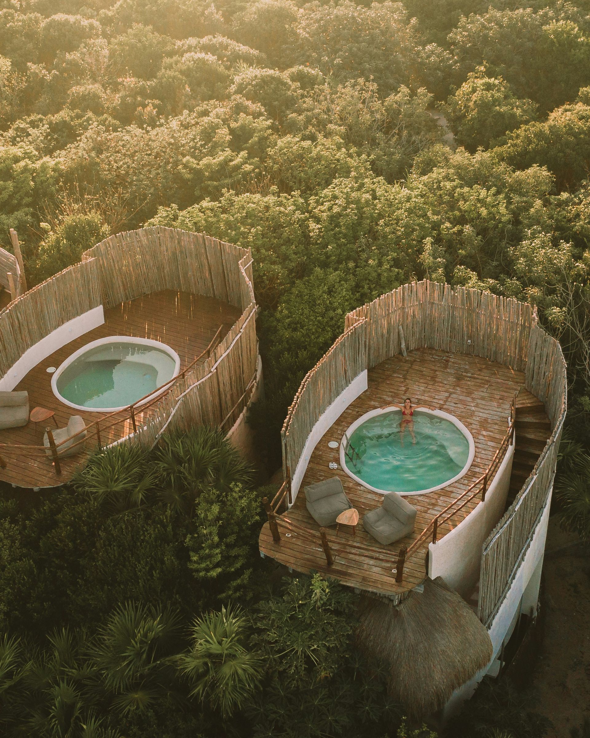 Aerial view of two bungalows with rooftop pools, surrounded by lush green trees in Tulum, Mexico.