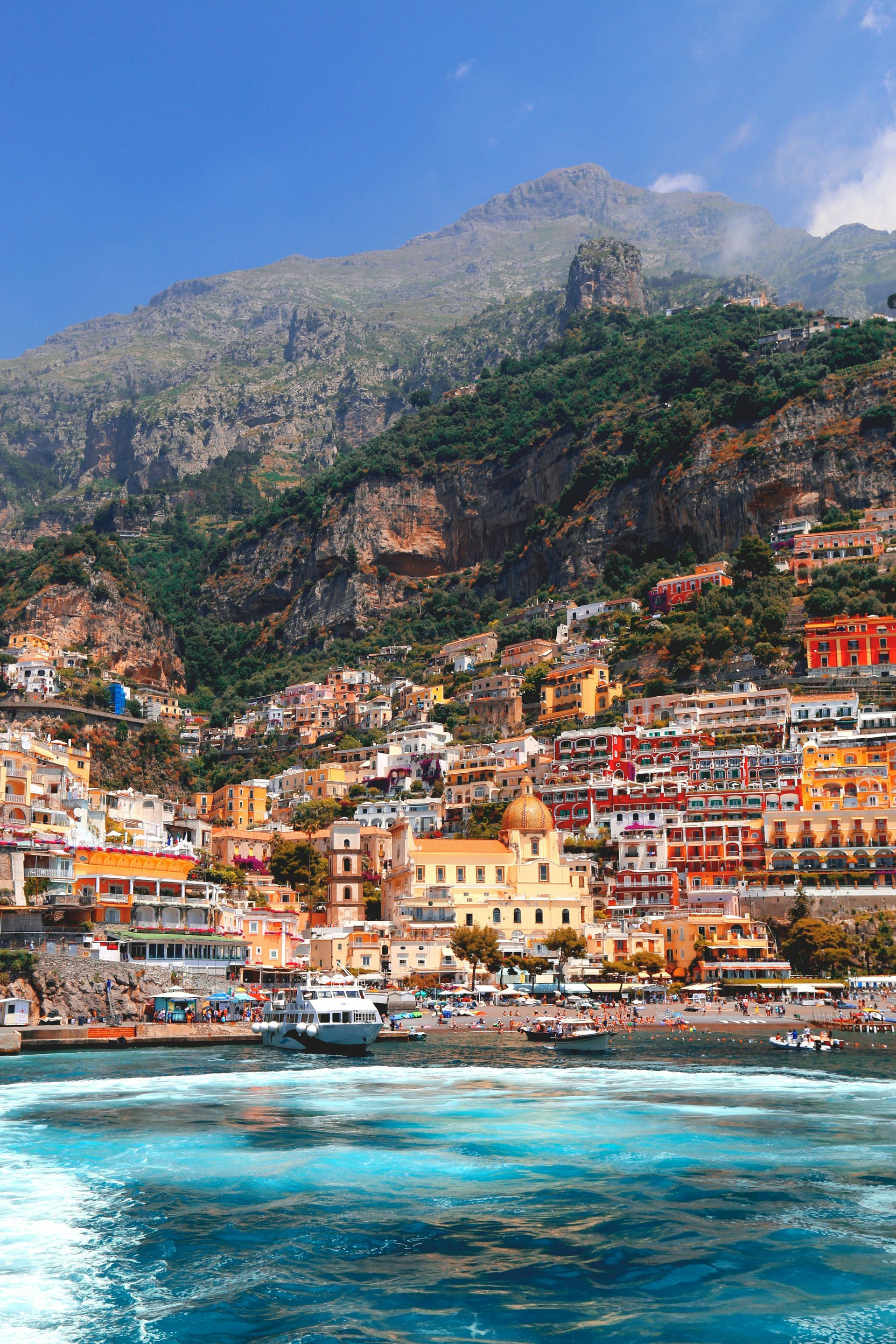A view of a city from the water with a mountain in the background on the Amalfi Coast.