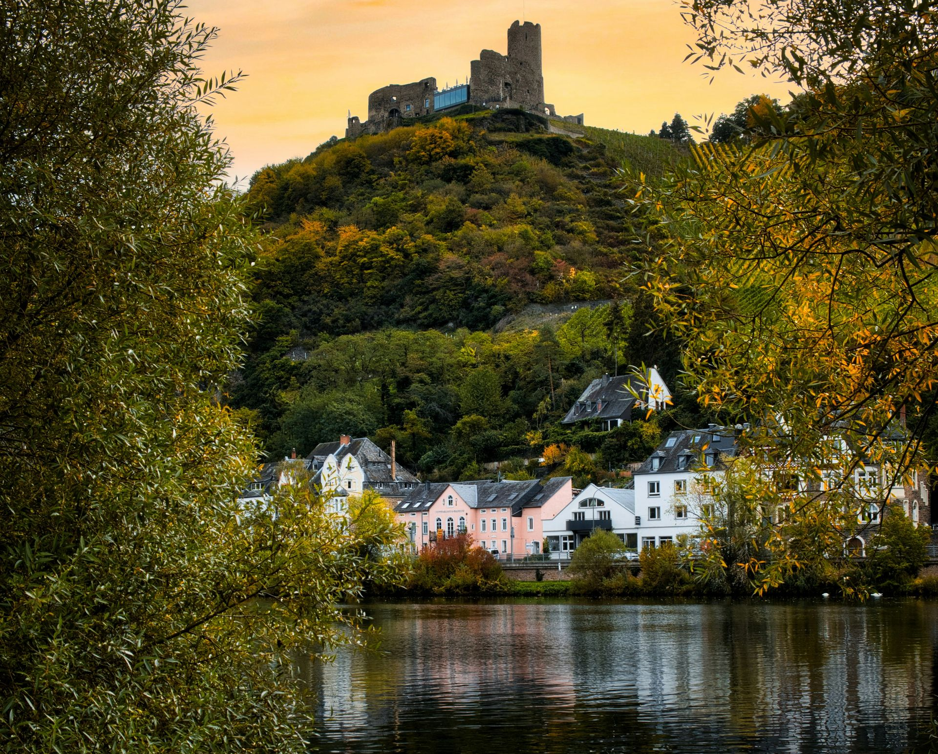 Castle on a hill overlooking the Moselle River and colorful houses, autumn trees in Germany