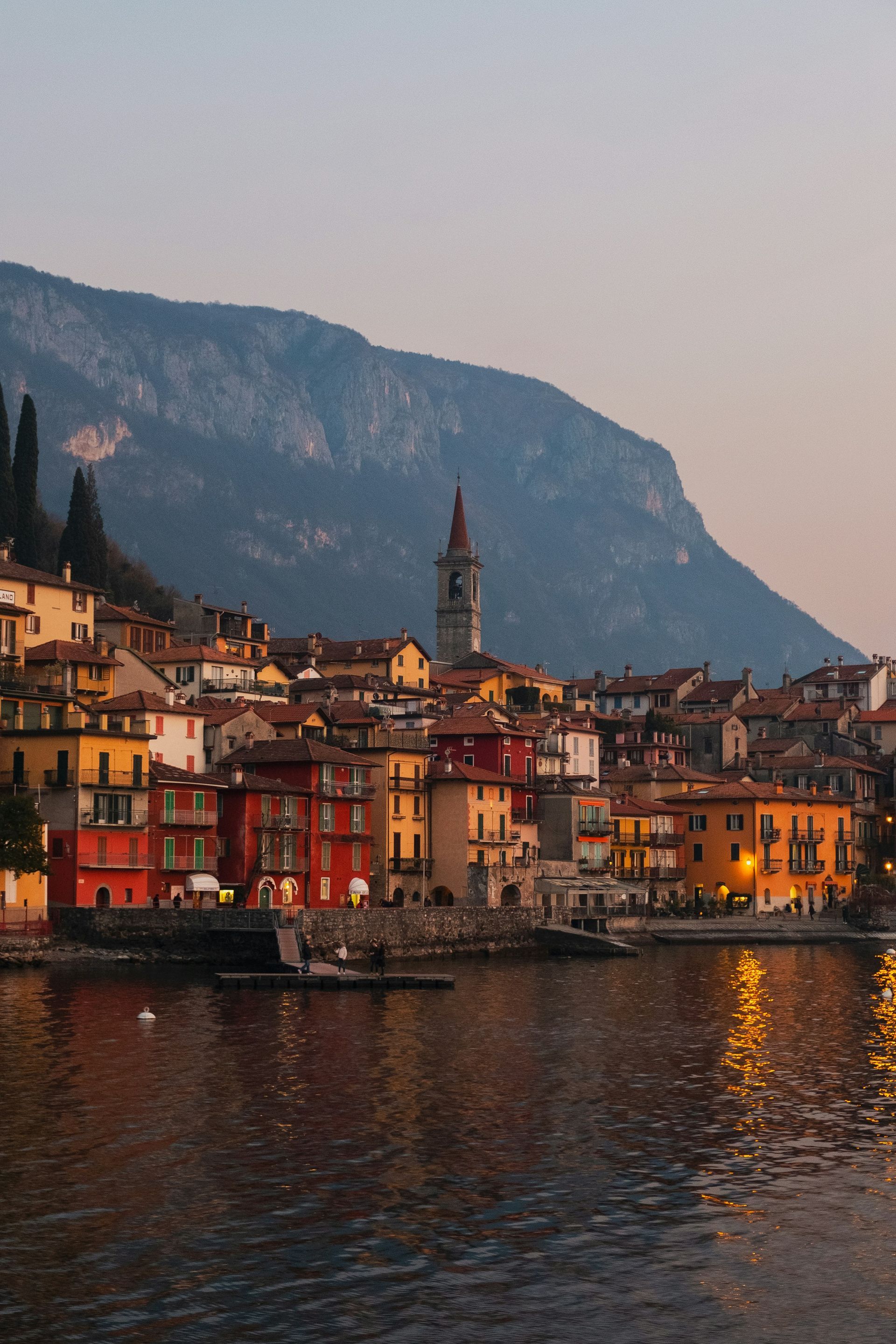A small town on the shore of Lake Como with a mountain in the background in Italy.