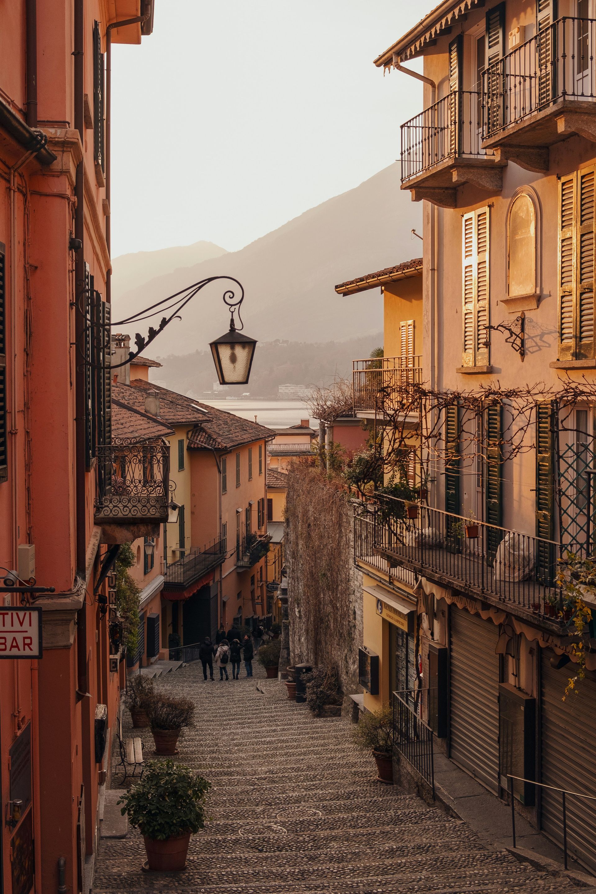 A narrow cobblestone street between two buildings with a lake in the background on the Amalfi Coast.