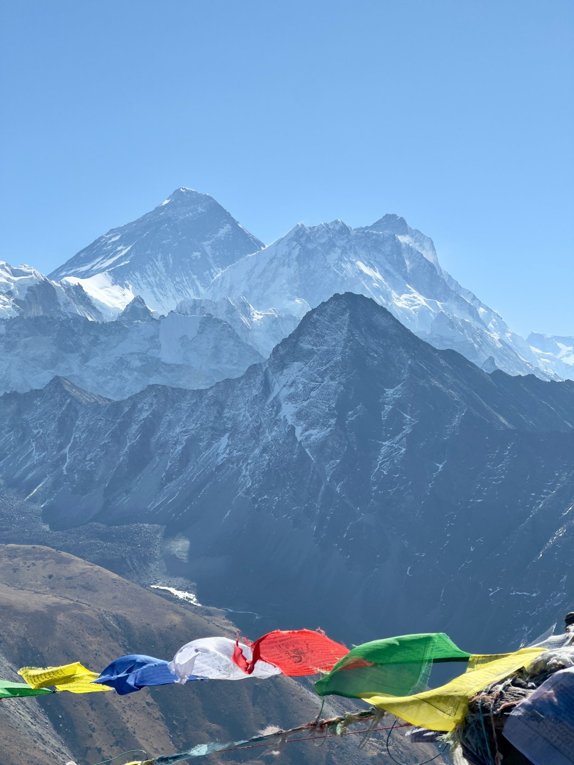 Snow-covered mountains, including Everest, with colorful prayer flags in the foreground in Sagarmatha, Nepal.
