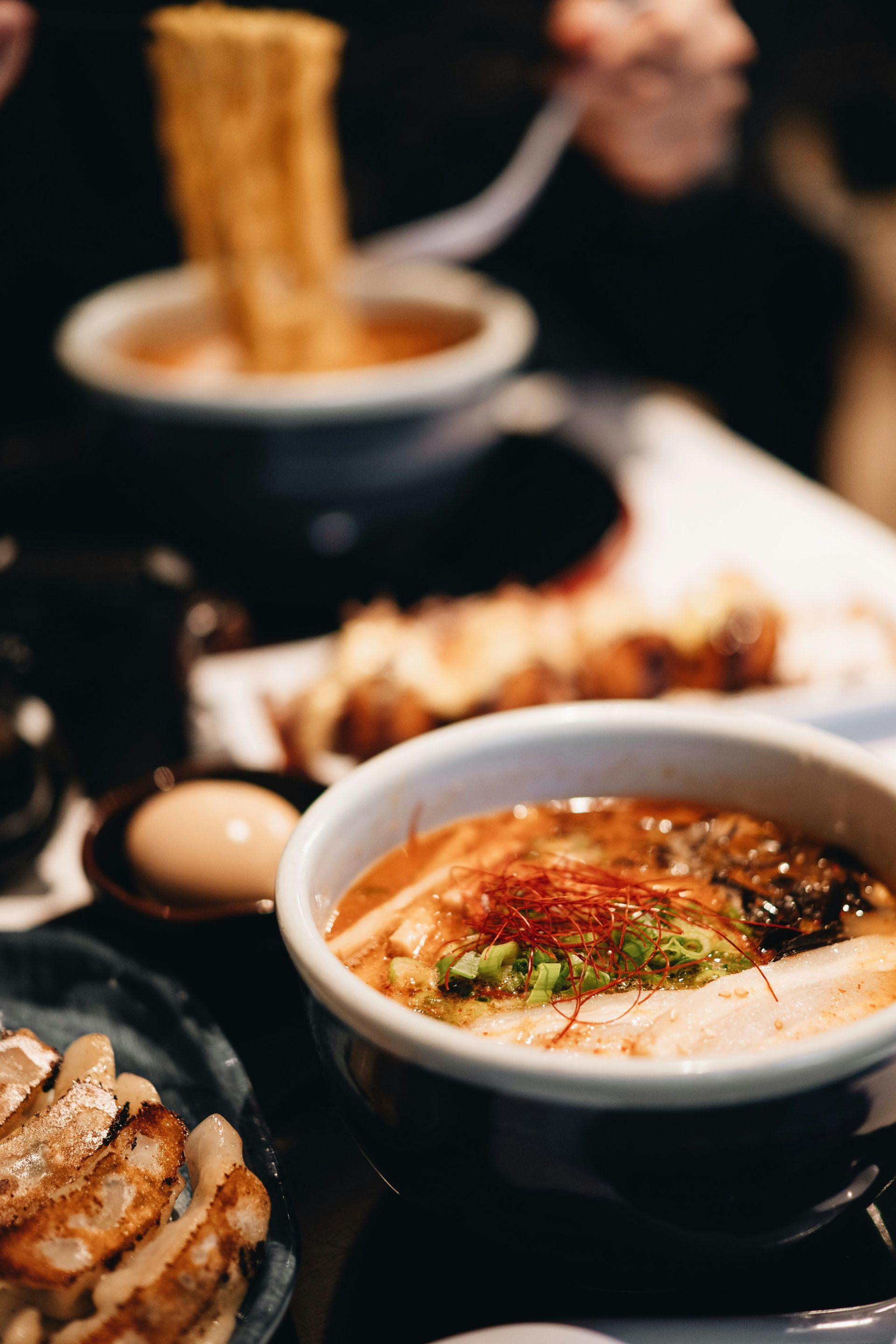 Bowls of ramen with toppings on a table with other dishes in Japan.