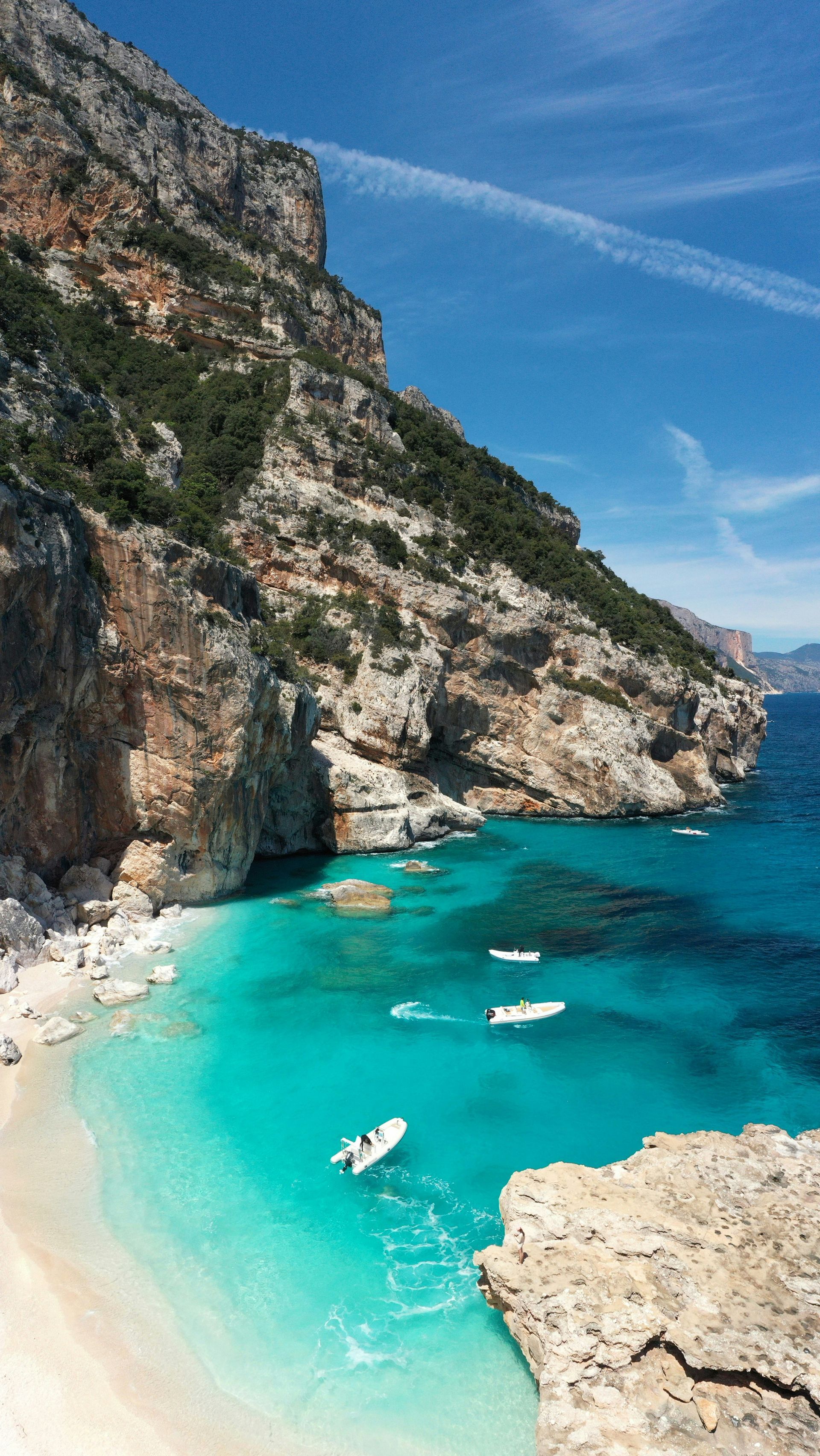 There is a boat in the water near the beach in Sardinia, Italy.