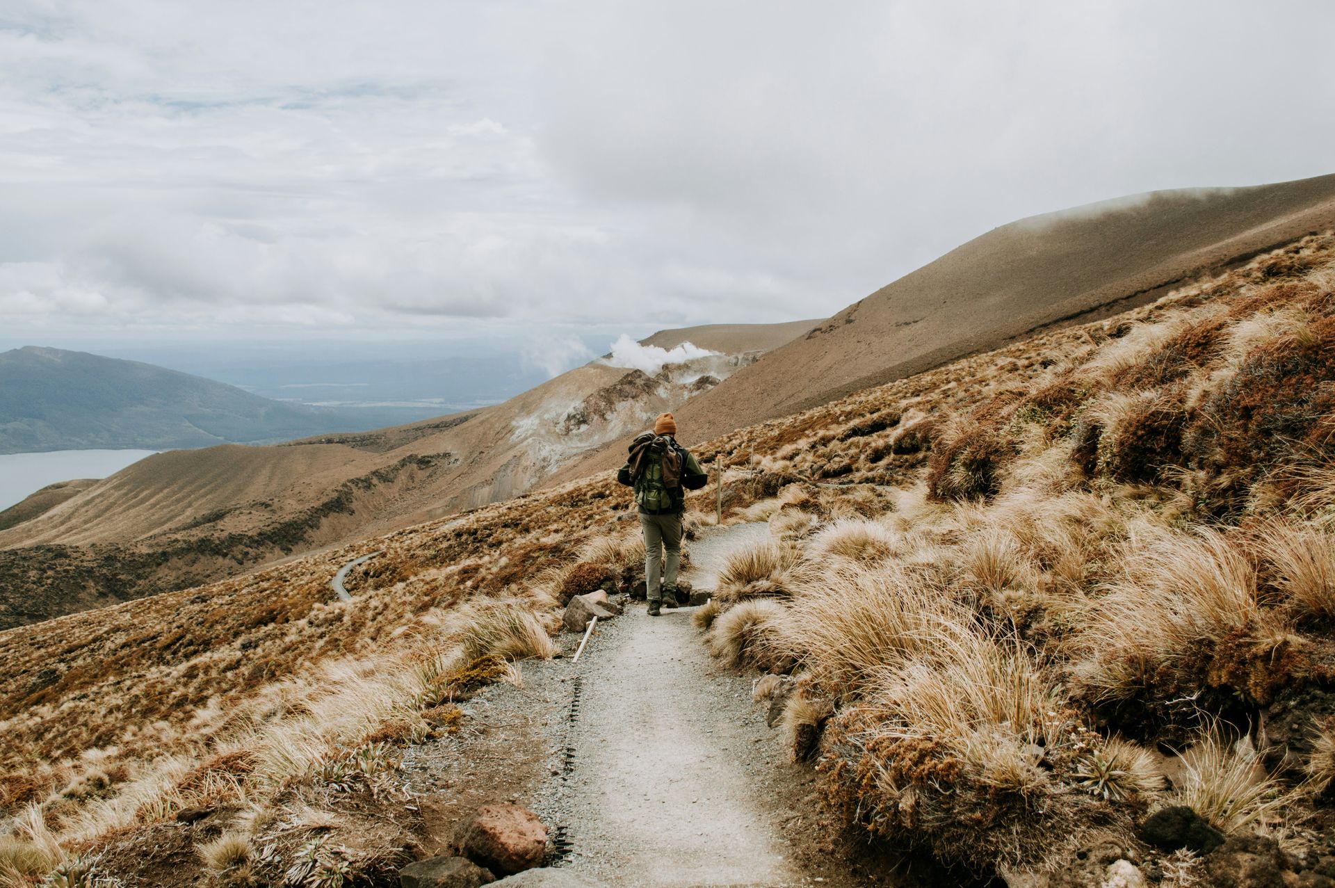 A person is walking down the Tongariro Alpine Crossing in the mountains in New Zealand.